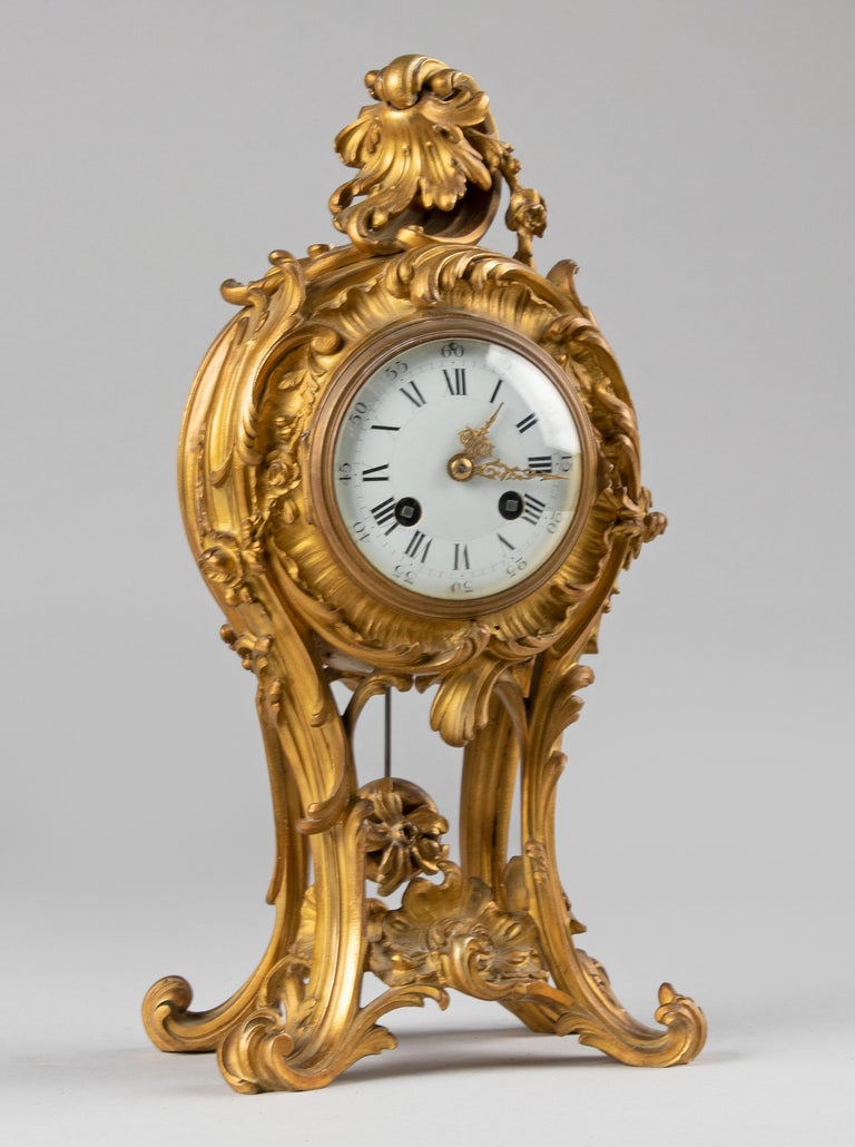 An elegant French mantel clock/pendule, made of gilt bronze. The whole in Louis XV style. The clock is made in France 1880-1890. Fine bronze case with typical asymmetric floral motifs in Rococo style. The dial is enameled, at the Roman number VI is