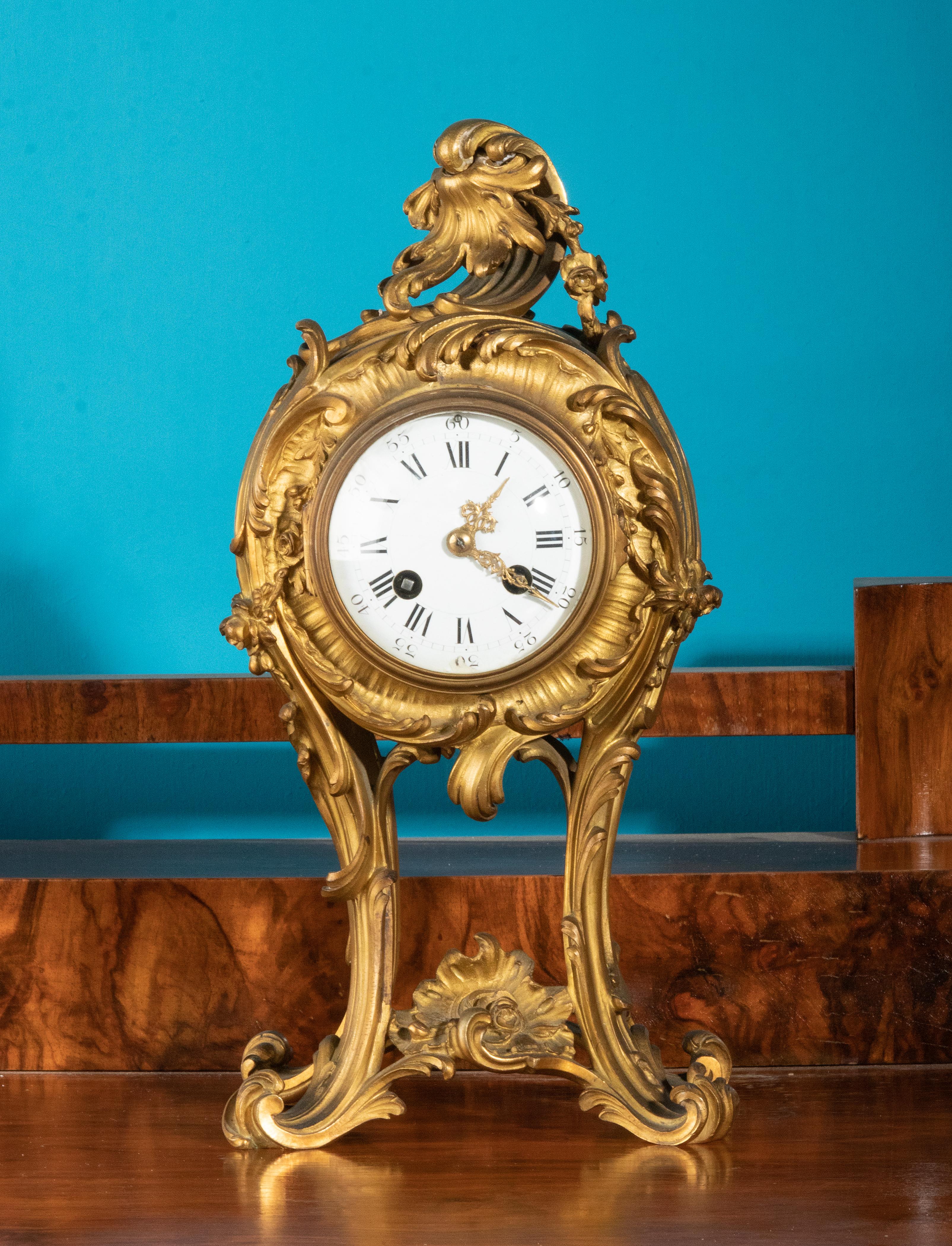 An elegant French mantel clock/pendule, made of gilt bronze. The whole in Louis XV style. The clock is made in France 1880-1890. Fine bronze case with typical asymmetric floral motifs in Rococo style. The dial is enameled, at the Roman number VI is