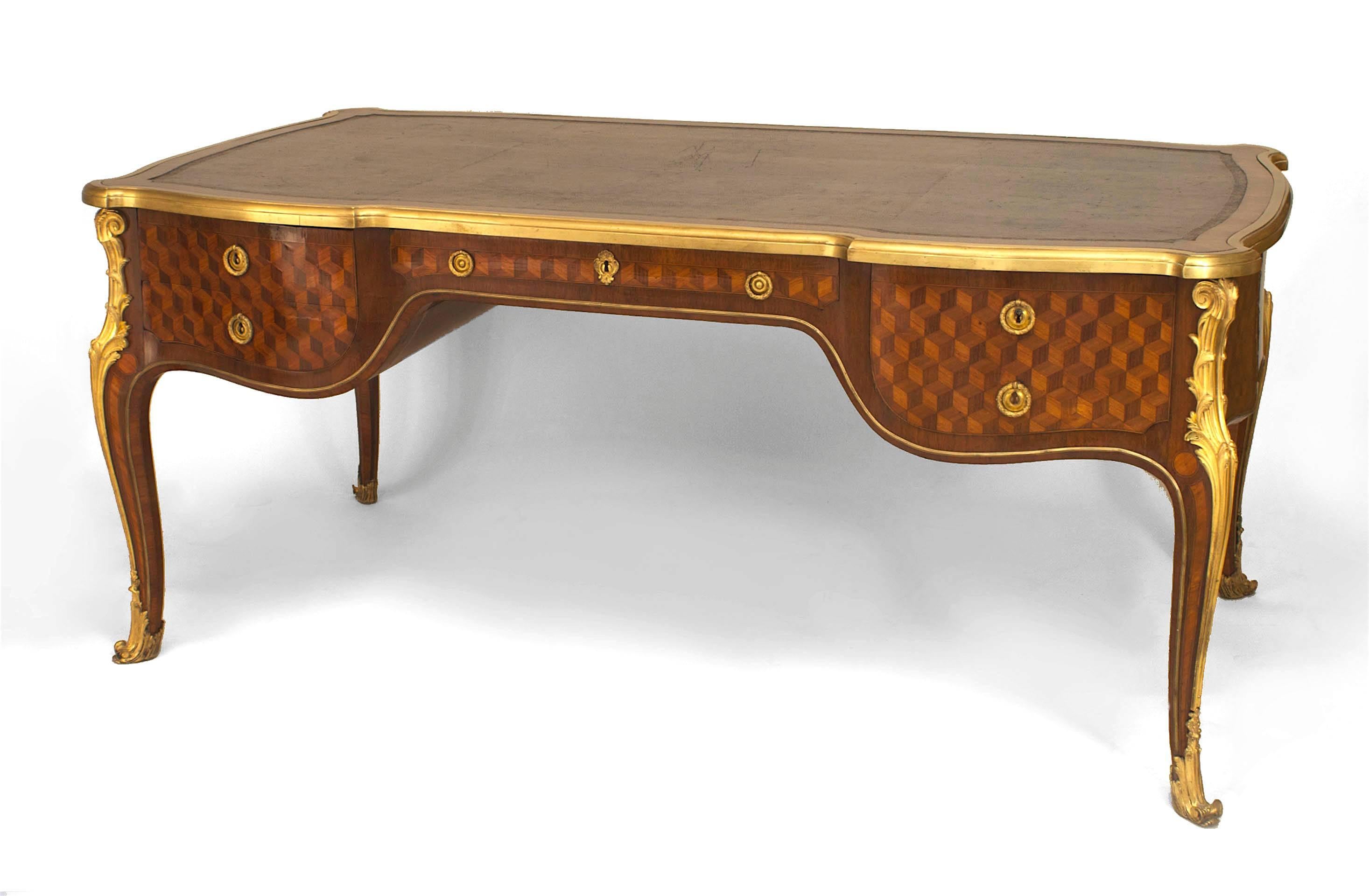Louis XV style (19th Century) parquetry inlaid gilt bronze trimmed bureau plat desk with a leather top bordered with mahogany over 5 drawers supported on cabriole legs.

