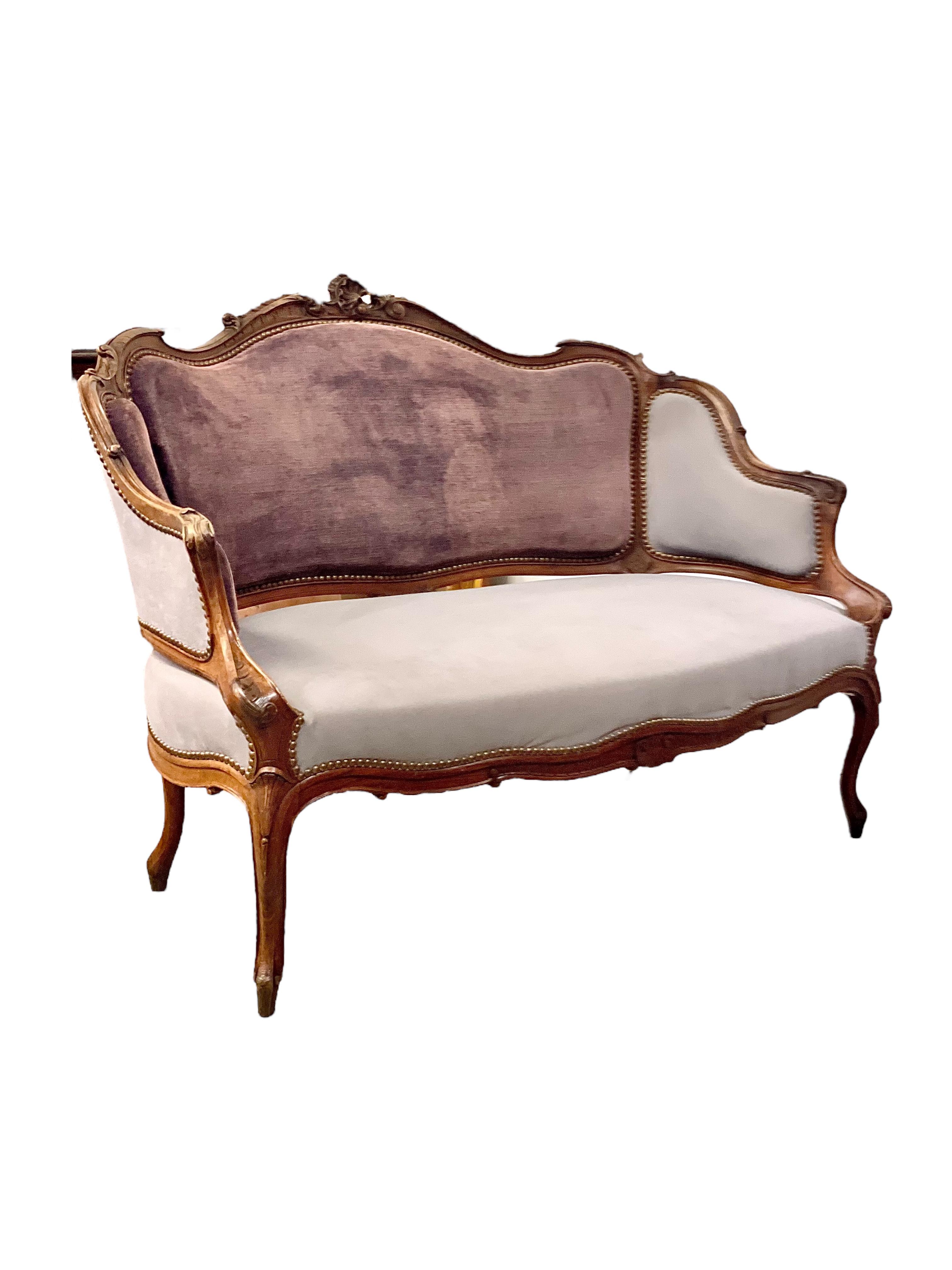 Questo squisito divano a due posti in stile Luigi XV del XIX secolo esemplifica l'eleganza e la maestria del design francese. La silhouette graziosamente curva, gli intagli intricati e i materiali di lusso rendono questo pezzo una vera e propria