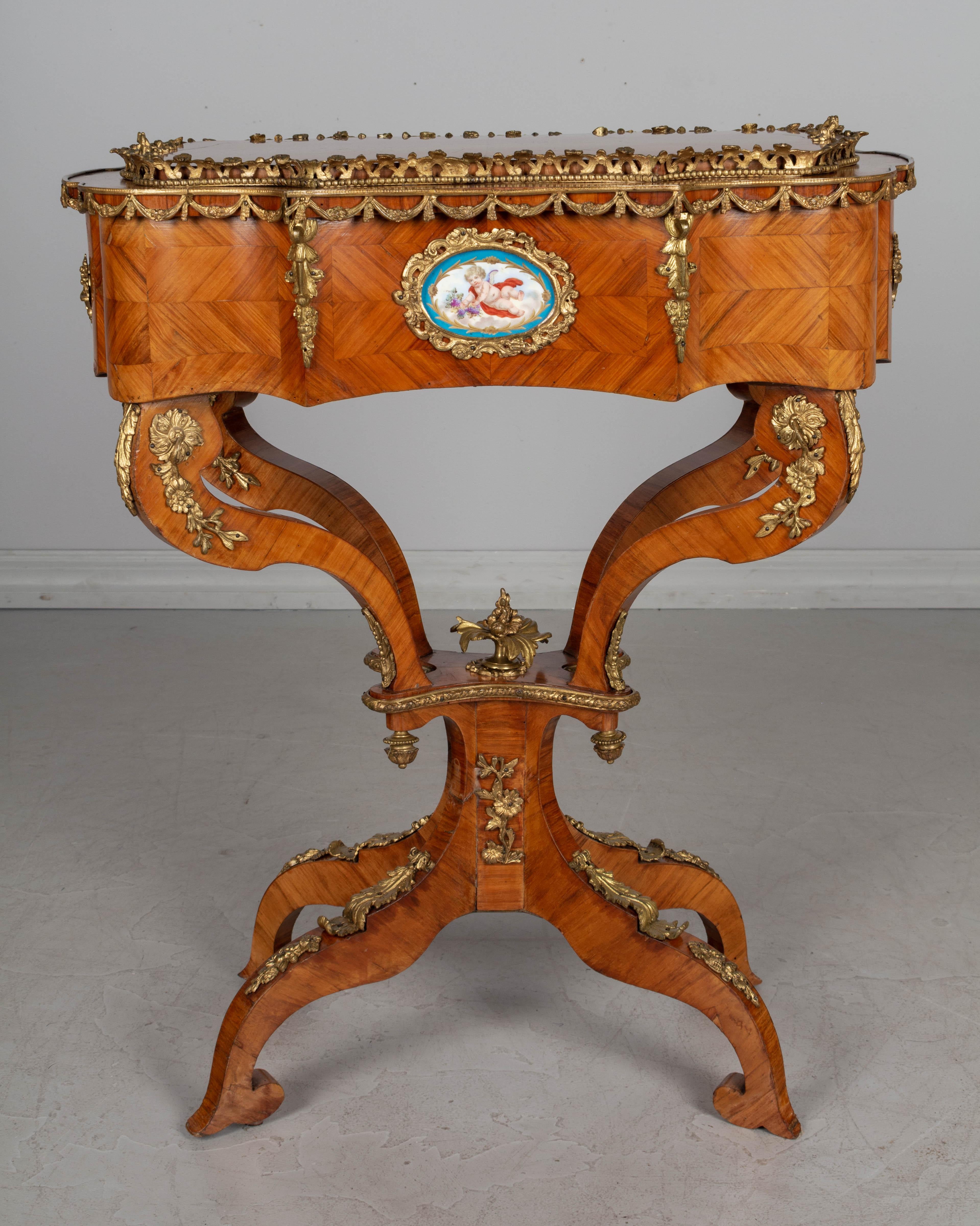 A 19th century French Louis XV style Rococo bronze mounted jardinière, or planter, on a pedestal stand. Kingwood marquetry veneer retains the old French polish finish. Decorated with two Sèvres hand painted porcelain oval medallions. The top has