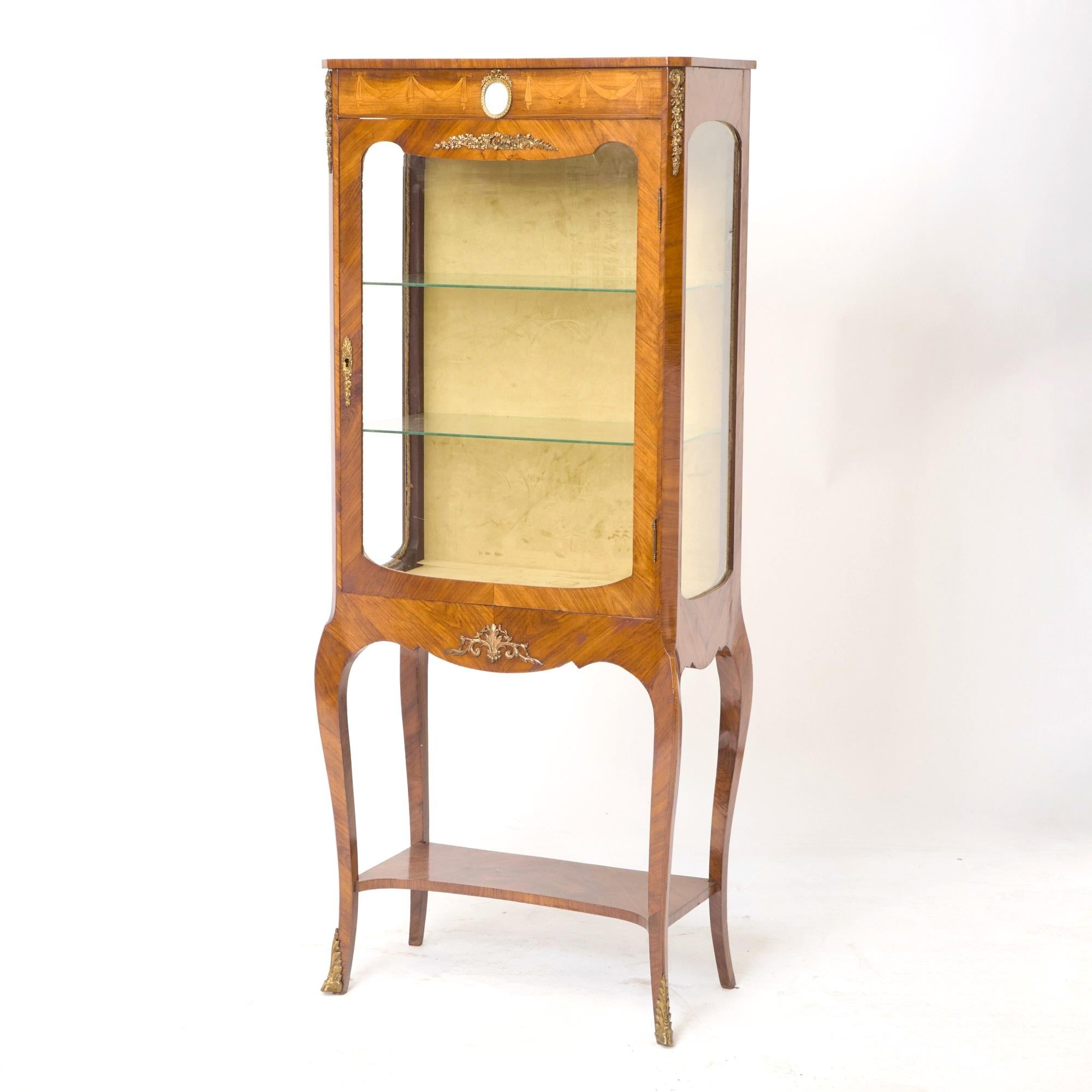 Un'elegante vetrina in stile Luigi XV del XIX secolo, che mostra un'eccezionale maestria francese e una raffinatezza senza tempo. Questo splendido pezzo è realizzato in lussuoso legno di re, ornato da intricati dettagli di intarsio e impreziosito da