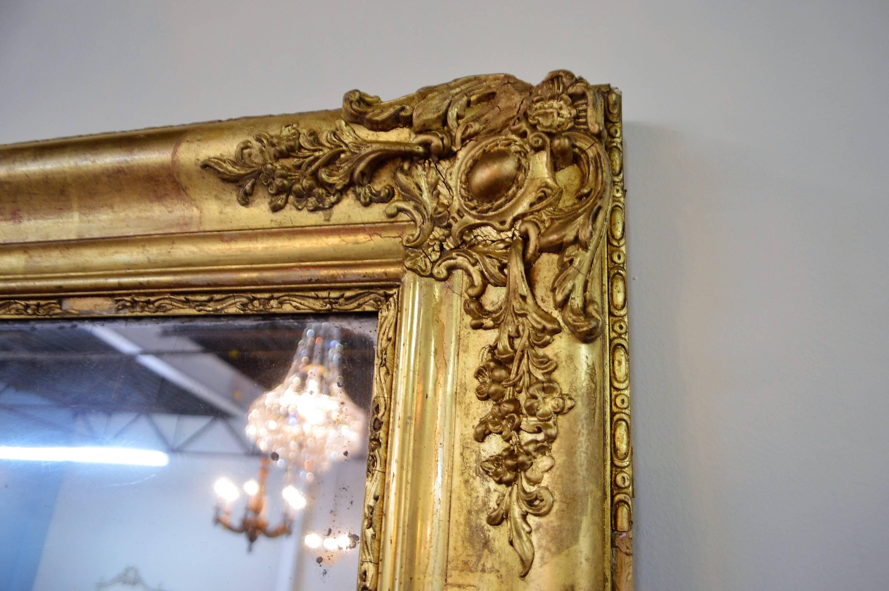 Mid-19th century Louis XV style large decorative mirror with carved details of medallions, flowers and acanthus leaves on all four corners and side of frame.
The original mirror was quite distressed, we have replaced it with a new beveled mirror.