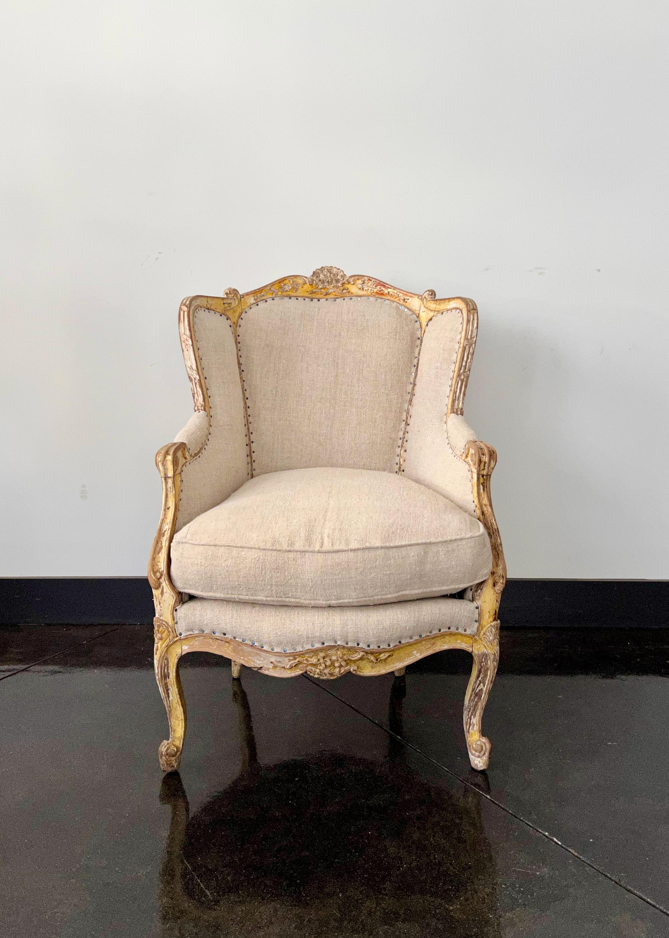 19th century French very wide and rare Bergère, Louis XV style in worn gold gilt with coved back which sweep without a break in to the armrests. Richly carved back and seat rails on elegant cabriole legs with flower carvings. Upholstered beautifully