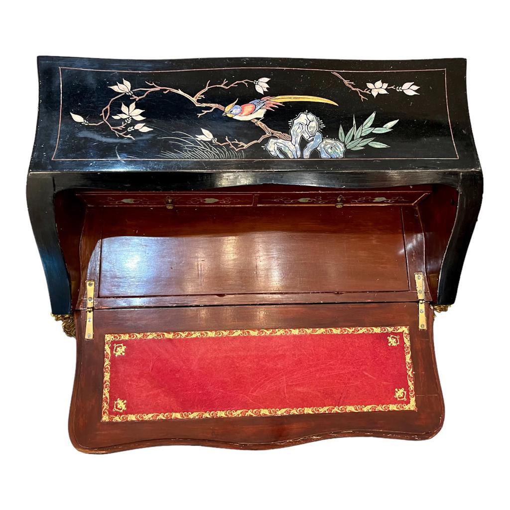 We present you a beautiful antique black slant-front desk in Coromandel lacquer, representing the opulent Louis XV style. The desk showcases images of scenes of Chinese daily life, teeming with vibrant depictions of people and nature birds set