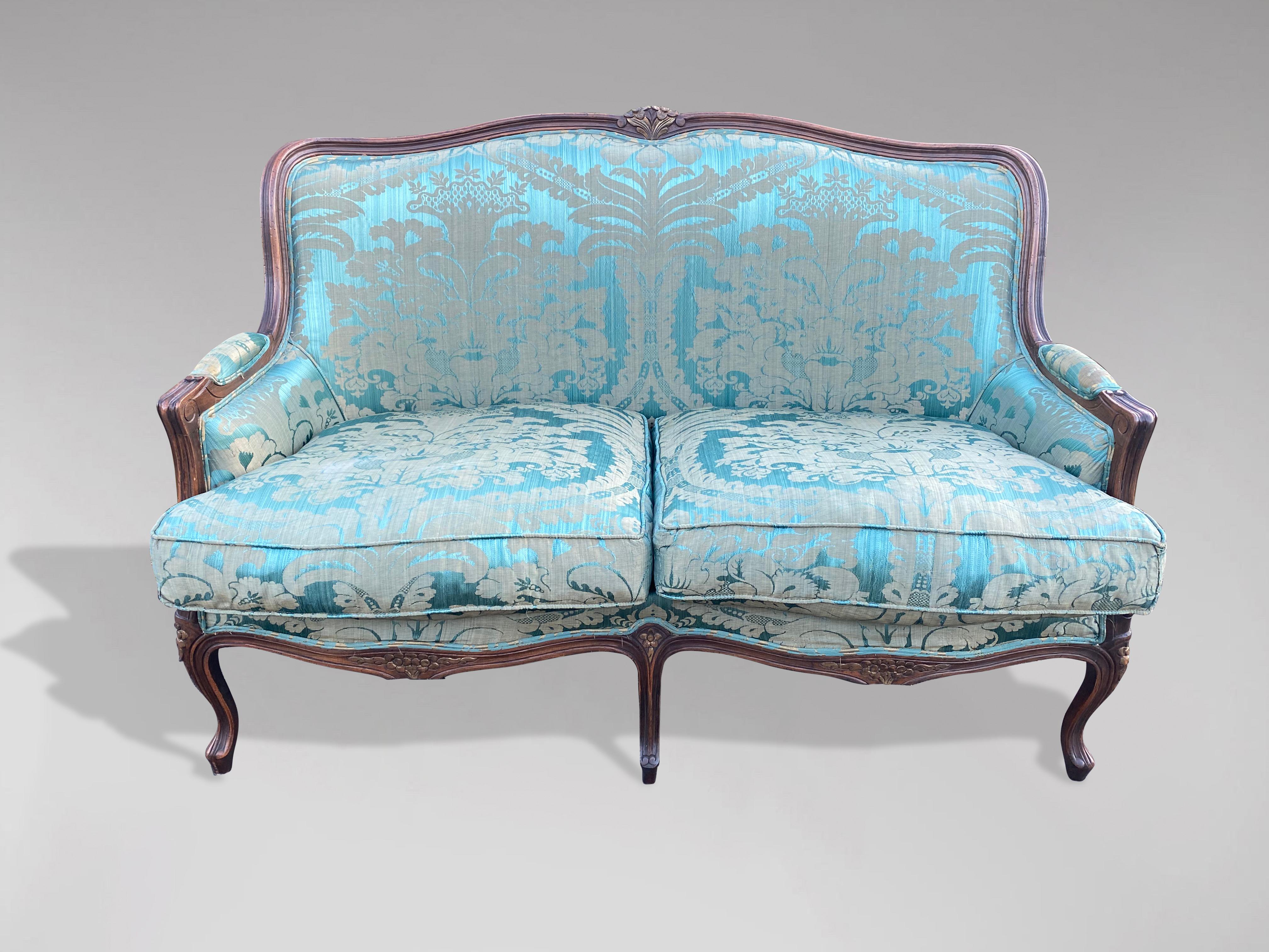 A late 19th Century French sofa in Louis XV Style, beech moulded frame carved with foliate detailing and curved back, standing on 5 elegant cabriole legs, upholstered in turquoise silk with two feather filled loose seat shaped cushions. The seat is