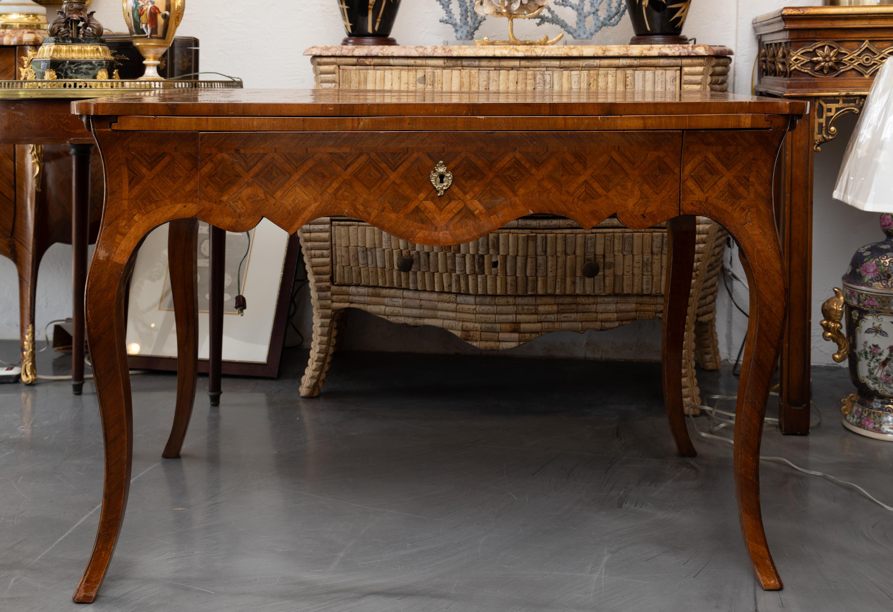 This is a lovely mellow 19th century French Louis XV style writing table with a parquetry top and a large concealed leather-inset brush slide that projects 19 inches in depth and 43 inches in length. The writing table also has a large parquetry