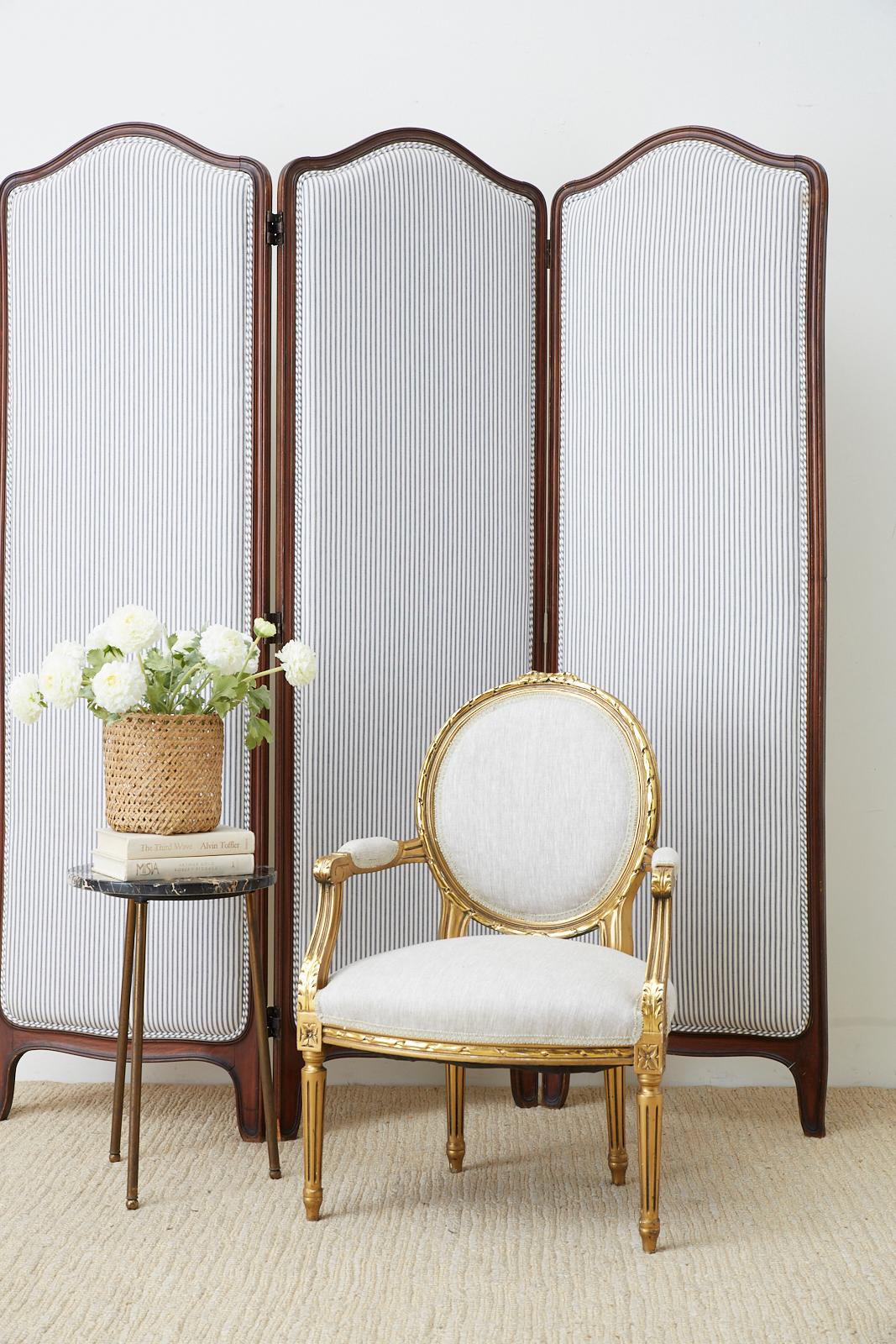Distinctive 19th century carved walnut three panel folding screen featuring a French ticking stripe upholstery. Made in the French Louis XV taste with a domed crest and shaped feet. The stripe pattern fabric is beautifully laid with a double welt