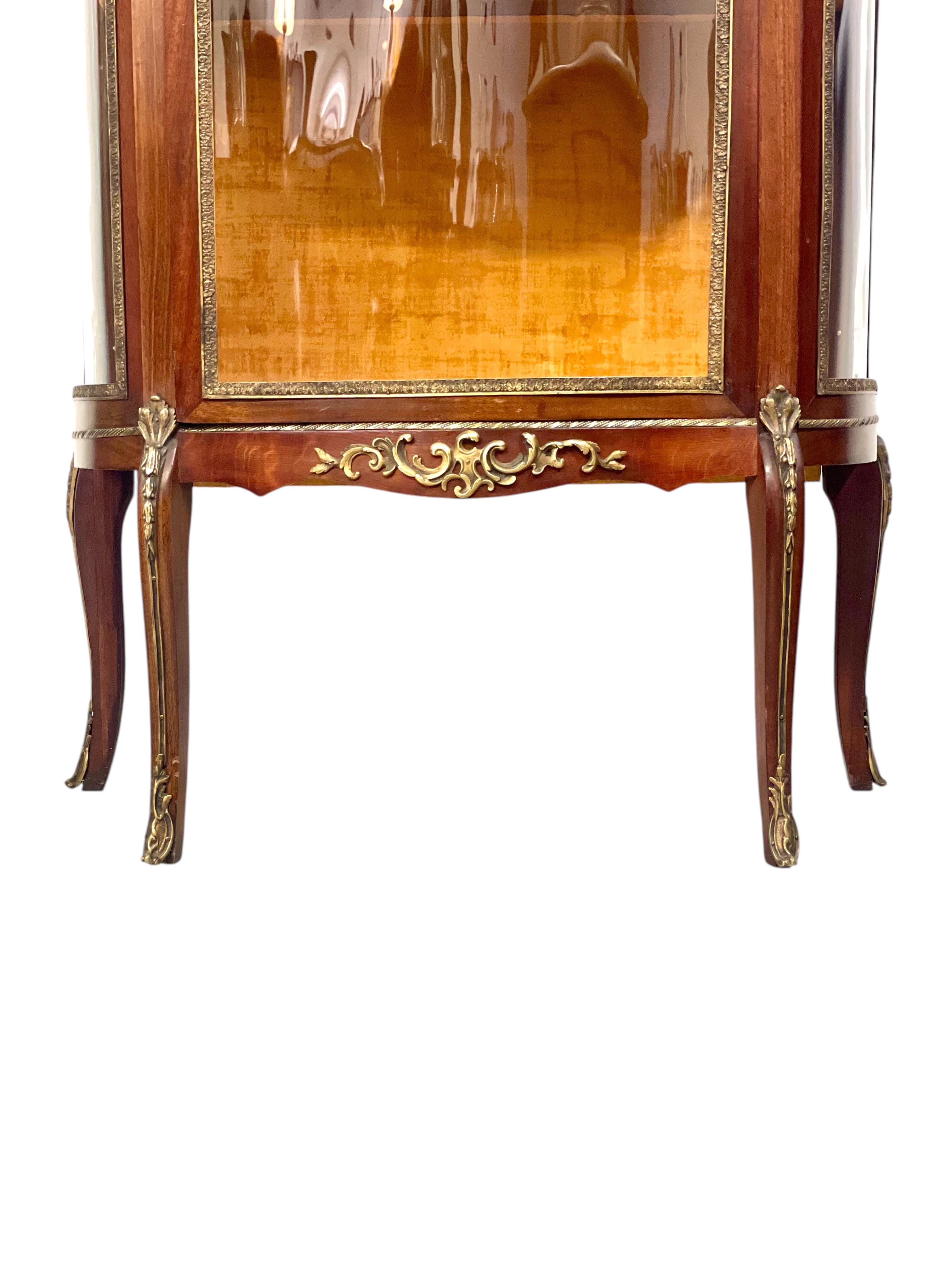 Impresionante vitrina francesa de estilo Luis XV de finales del siglo XIX, que combina elegancia, funcionalidad y fina artesanía. Esta vitrina presenta un elegante frente serpenteante y paneles laterales de cristal arqueados, que permiten una visión