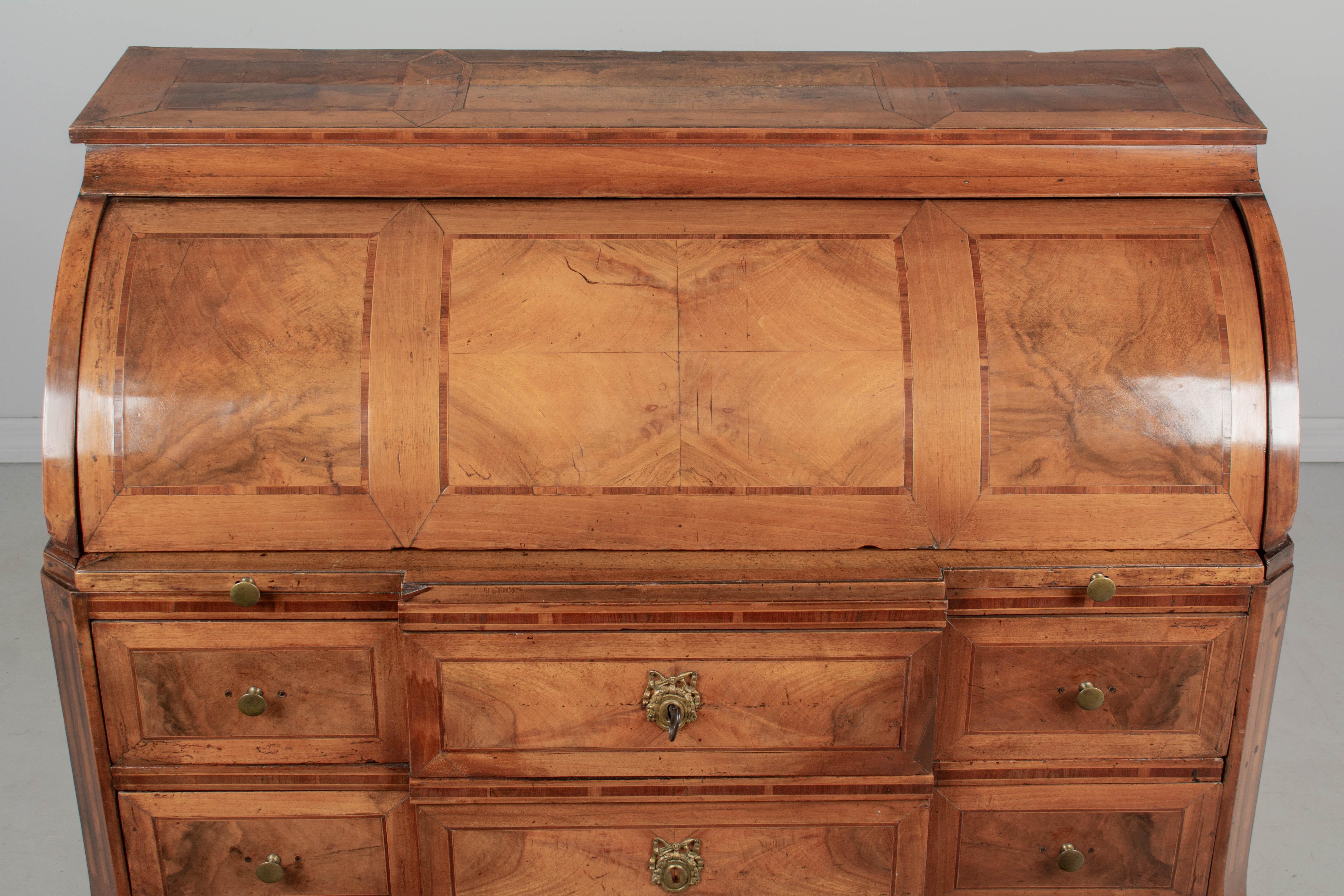 A fine early 19th century Louis XVI period bureau à cylindre, or roll top desk, made of solid walnut with marquetry veneers of walnut, mahogany and cherry. Pine as a secondary wood. The surface of the cylinder has book matched walnut veneer and