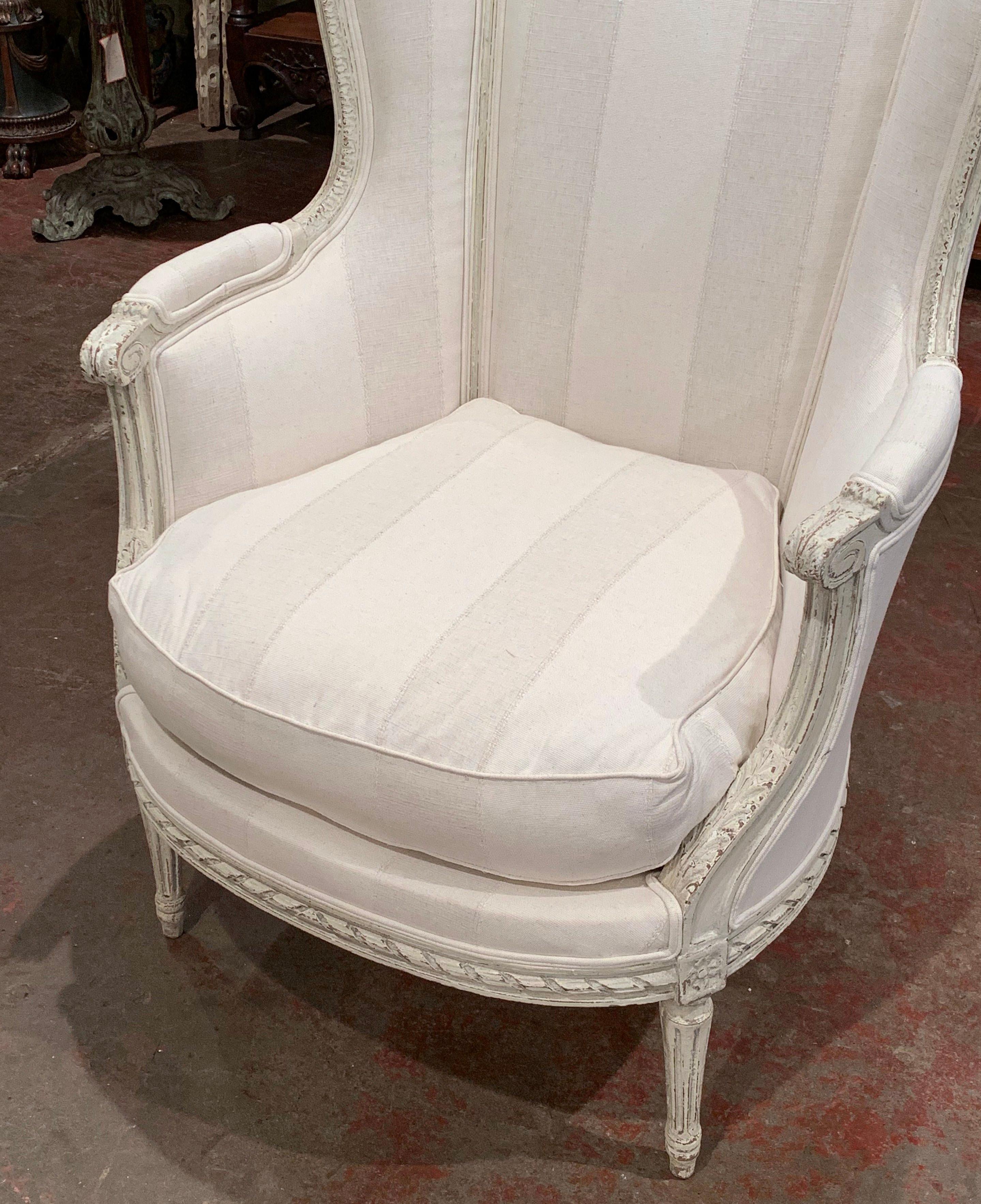 Decorate a bedroom or den with this elegant antique armchair. Crafted in France circa 1880, the chair sits on delicate tapered legs over a carved apron. The tall curved back is embellished with ear shaped sides and the armrests are decorated with