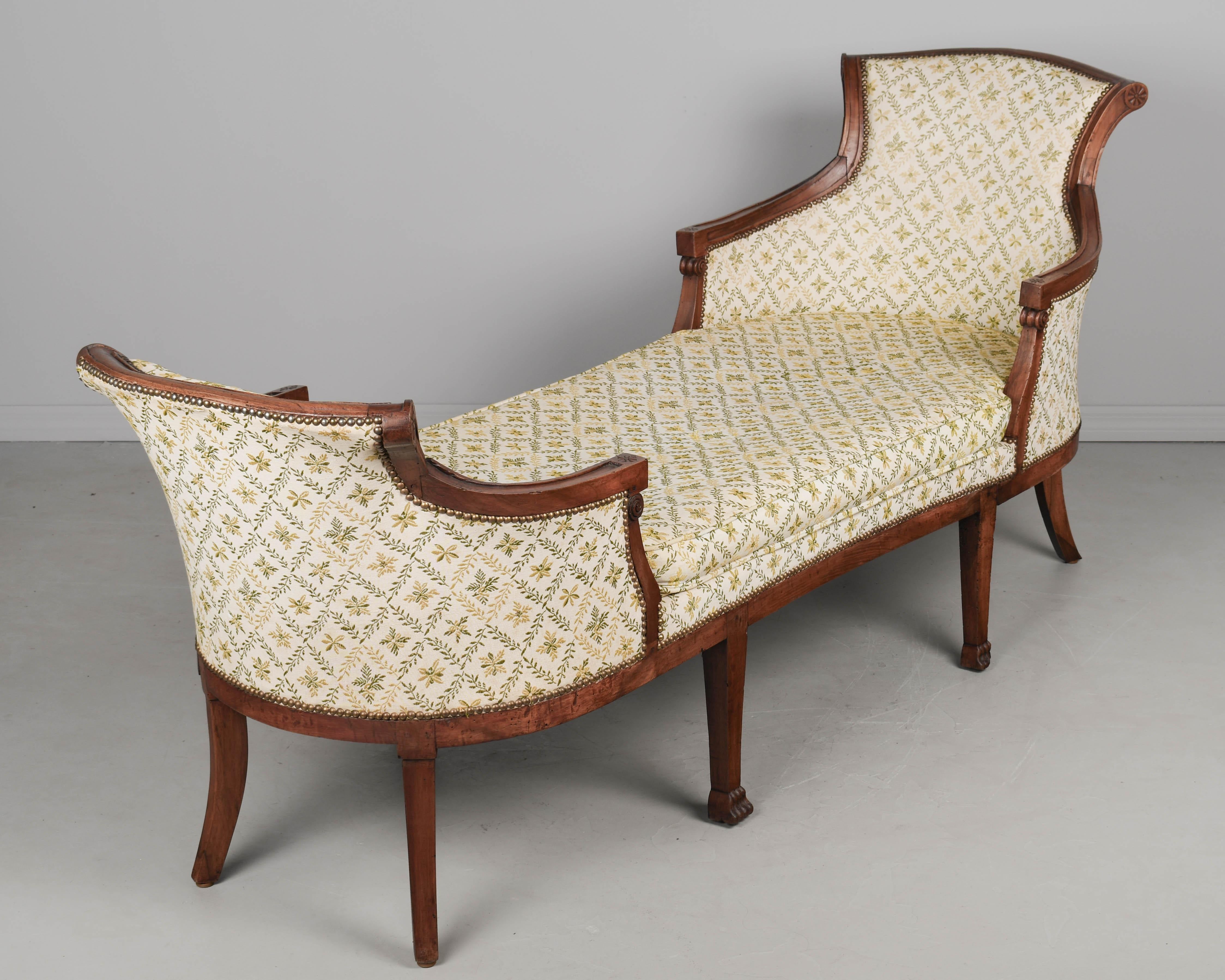 An early 19th Century French Louis XVI style duchesse en bateau, or chaise longue by master furniture maker Pierre Pillot (1748-1822) of Nîmes. Solid walnut frame with hand-carved details and brass nail head trim. Upholstery is in serviceable