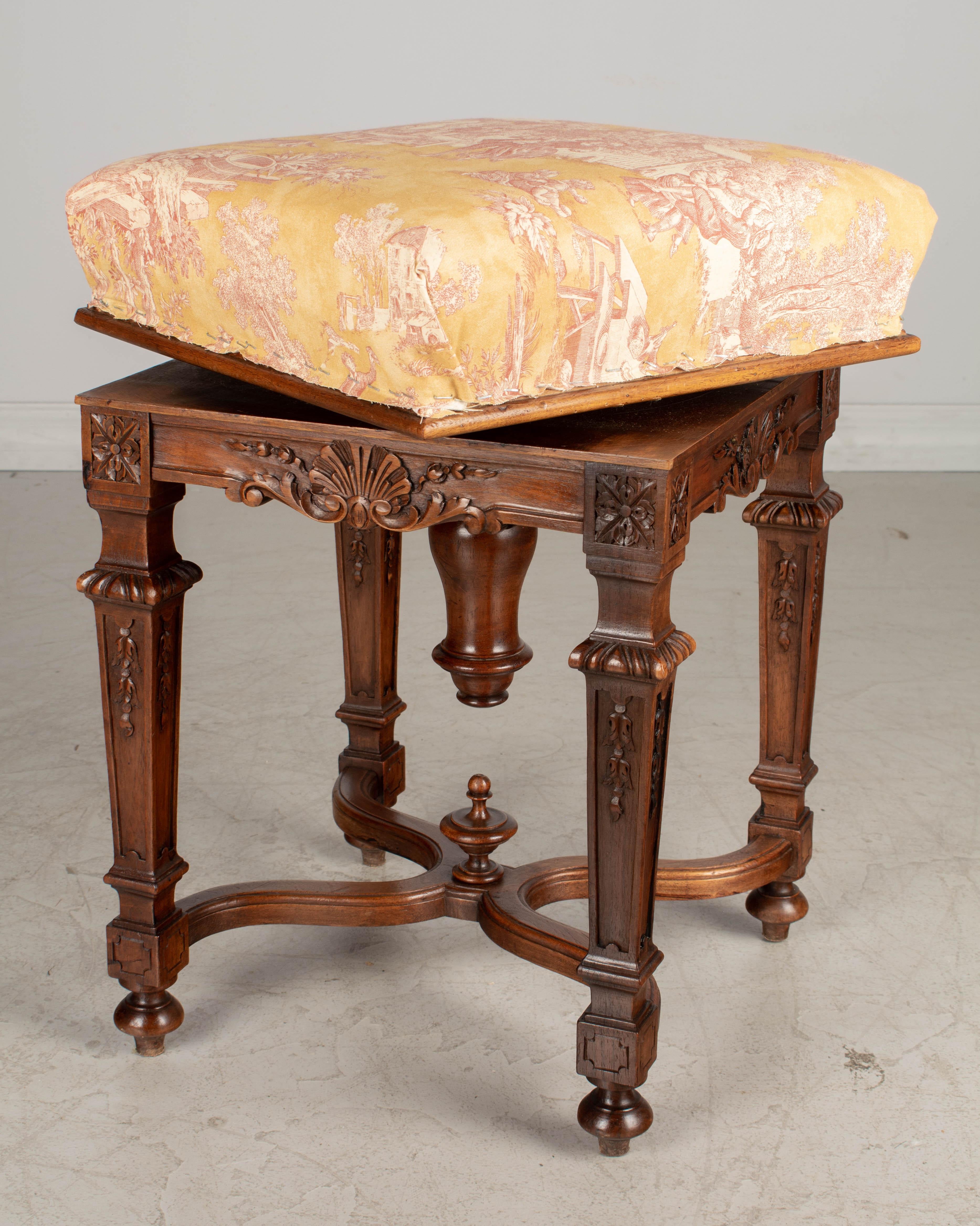 A 19th century French Louis XVI style adjustable swivel stool made of solid hand carved walnut with x-stretcher and wood finials. The seat of this small stool may be easily adjusted to a height of 21.5-26