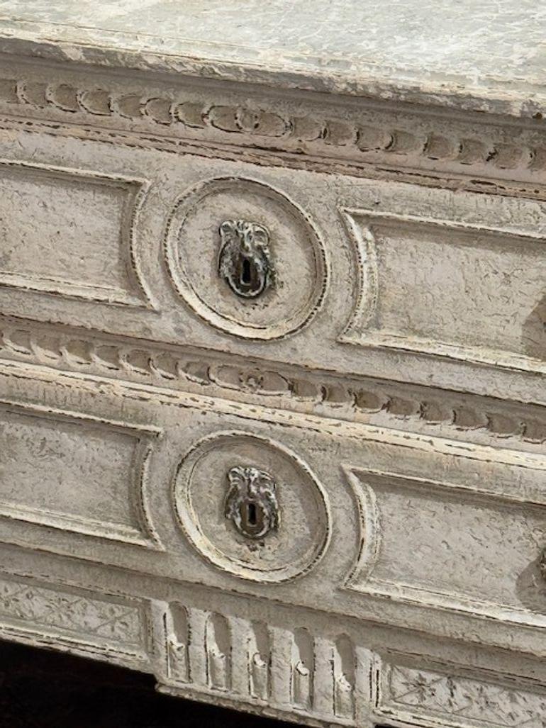 La Commode francese intagliata e dipinta del XIX secolo è un mobile straordinario che emana eleganza e raffinatezza. La commode presenta intricati intagli e una finitura dipinta in stile Luigi XVI, noto per i suoi elementi di design neoclassico.