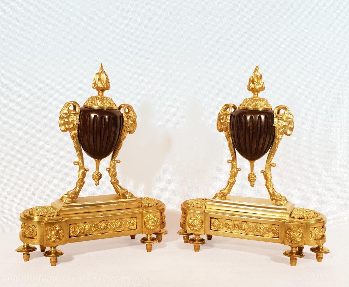 Pair of gilt and patinated bronze andirons. Depicting a fluted and patinated bronze firepot, supported by ram's heads and connected to the base by 4 feet with foliated hoofs.
Beautiful quality of casting and chasing, gilding in excellent