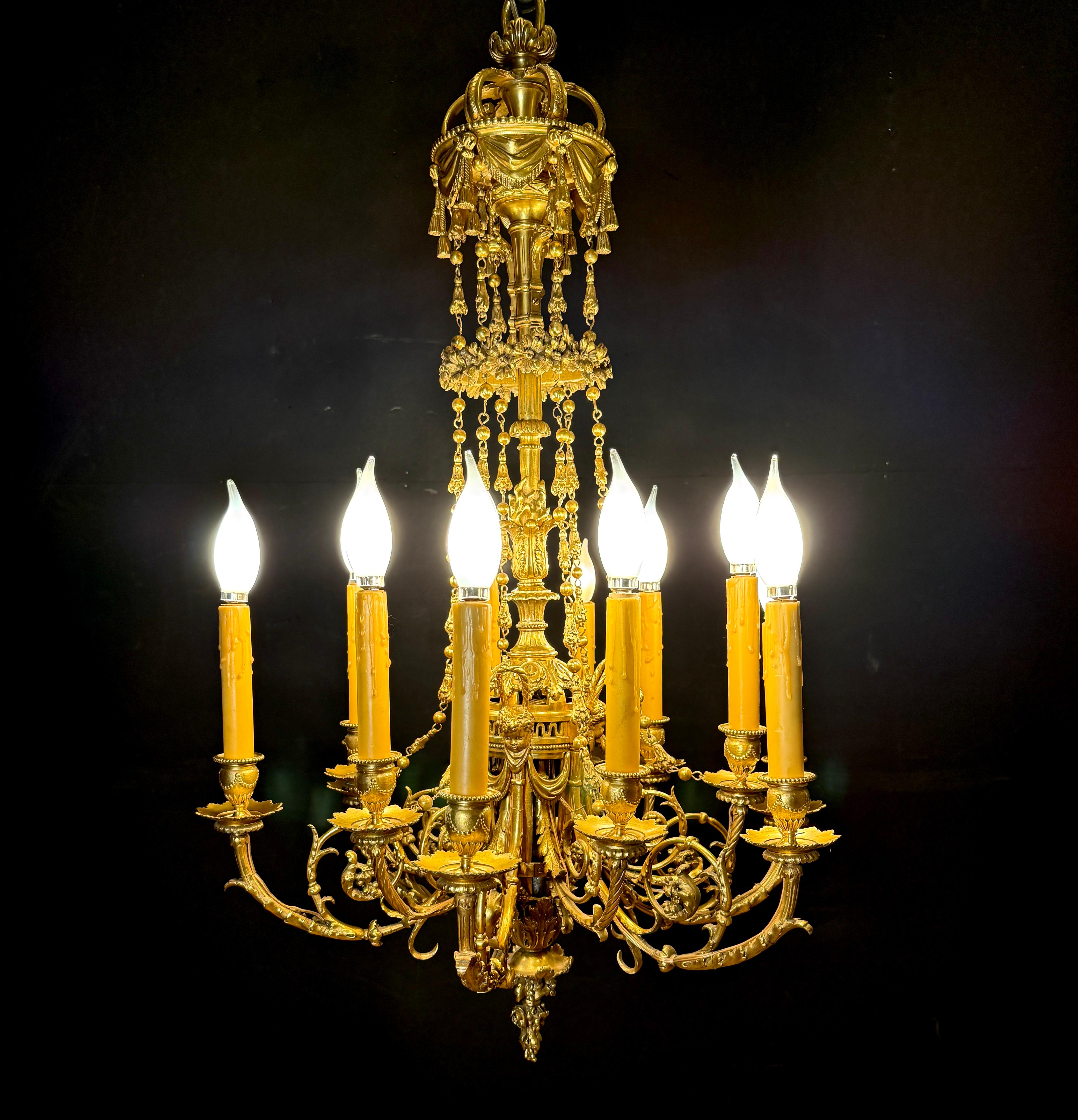 Exceptionnel lustre à douze lumières en bronze doré de style Louis XVI du XIXe siècle, richement moulé avec de superbes détails néoclassiques. Le lustre présente des bras élégants et larges, décorés de feuilles d'acanthe et supportant des lampes en