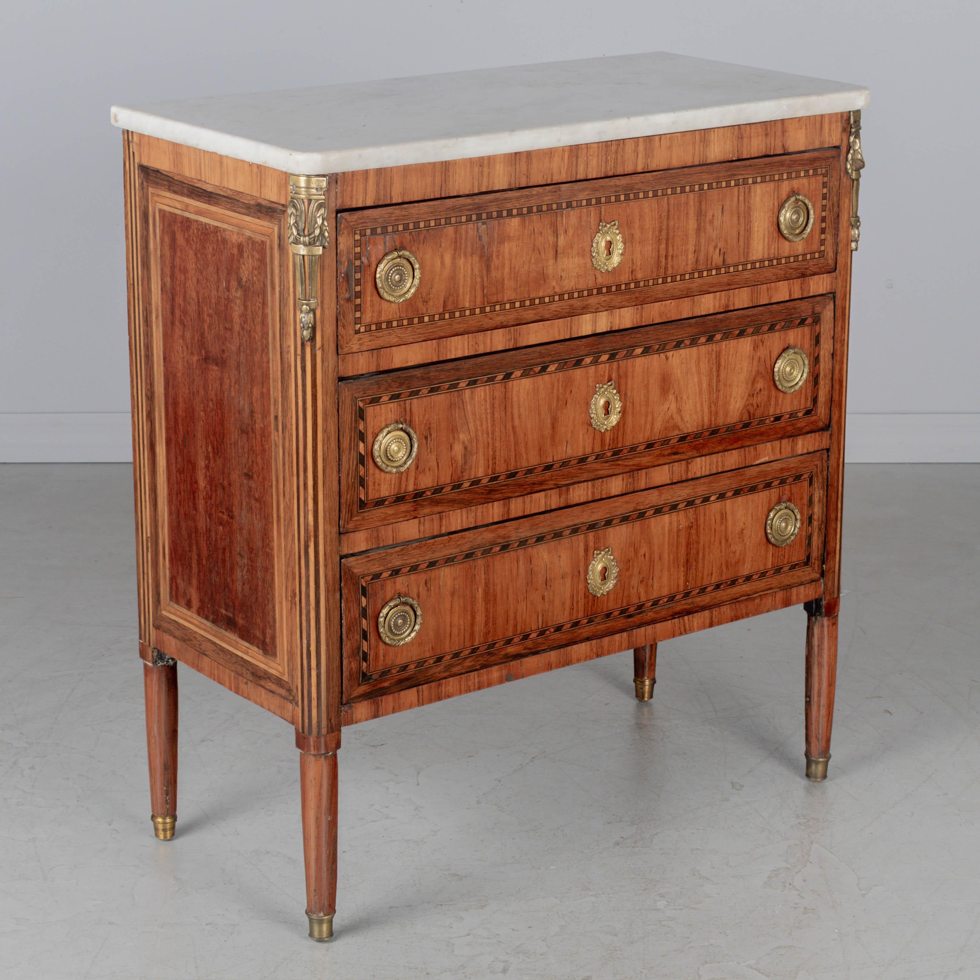 Commode française du XIXe siècle de style Louis XVI en marqueterie d'acajou avec placages d'acajou et de noyer. Trois tiroirs à queue d'aronde dont l'intérieur est tapissé de tissu vert. Quincaillerie en bronze moulé. Les écussons sont plus récents