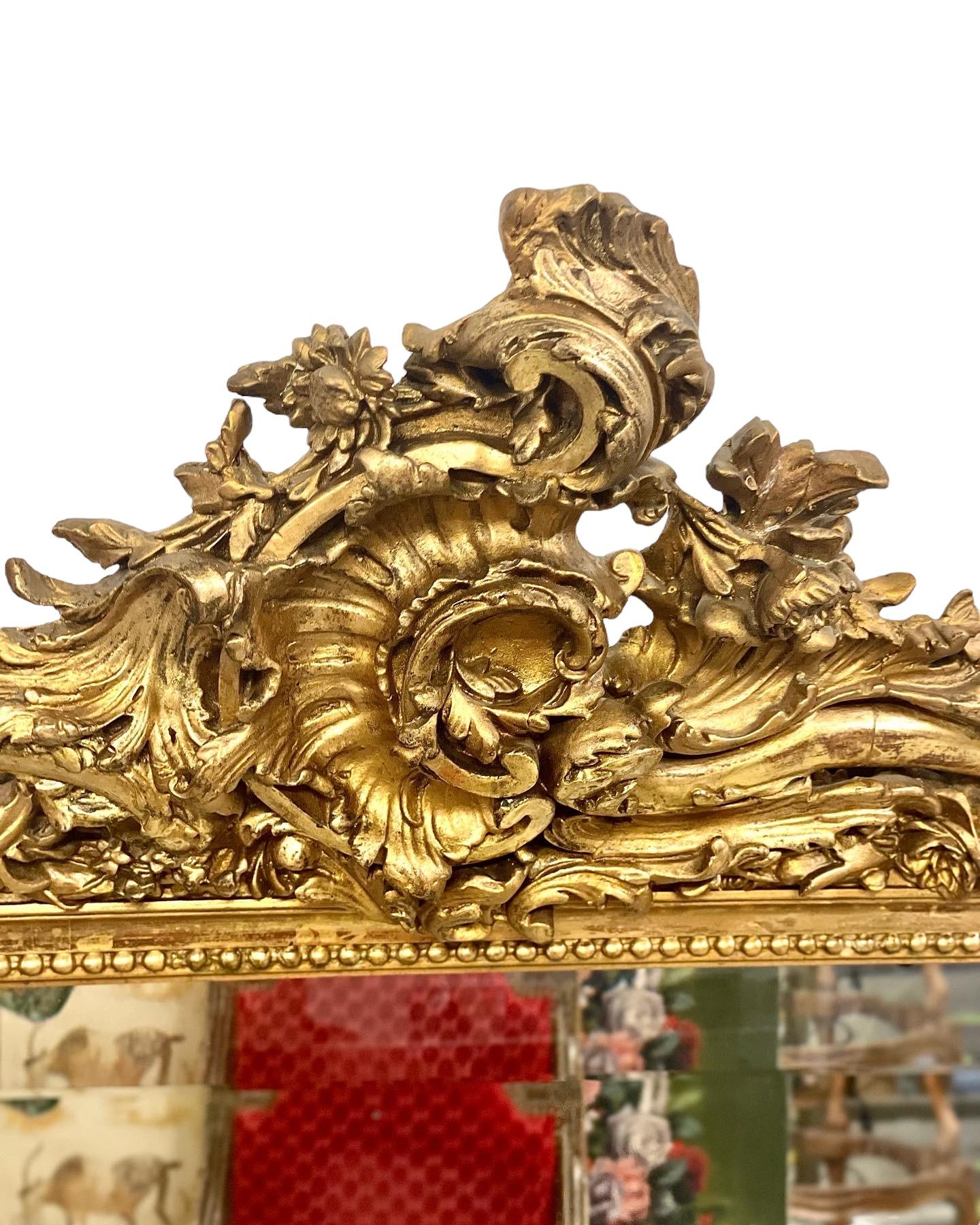 Spettacolare specchio da camino rettangolare del XIX secolo con cornice in legno dorato e stucco lavorato a mano e piastra a specchio smussata. La cornice riccamente intagliata di questo straordinario specchio presenta una patina splendidamente