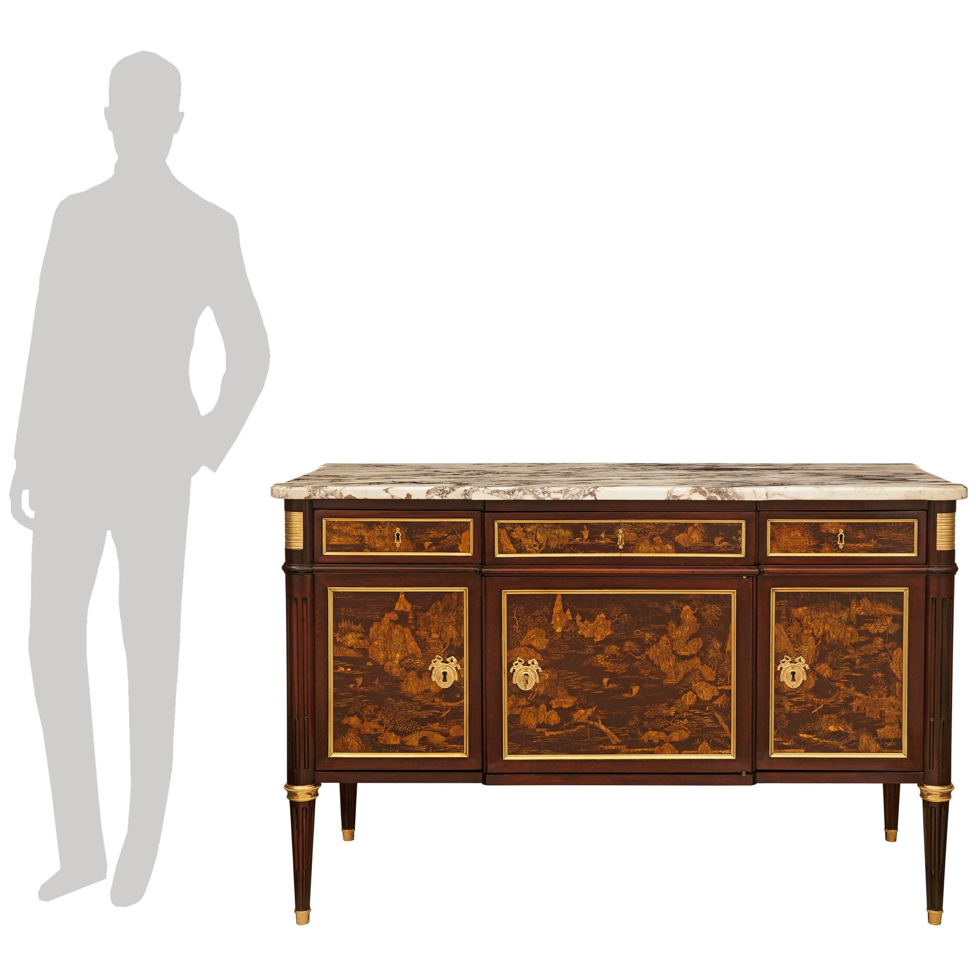 A handsome and most decorative French 19th century Louis XVI st. Mahogany, Ormolu, Japanese Lacquer and marble buffet. This elegant cabinet is raised on four circular tapered, and fluted legs with wrap around Ormolu sabots and beaded top bands.