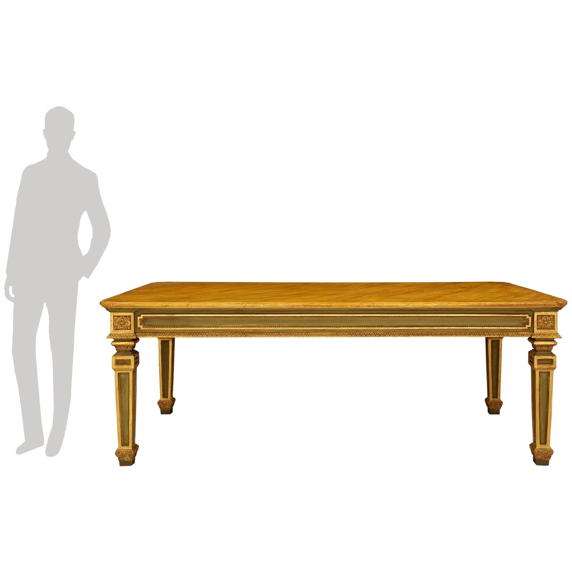 An impressive and high quality Italian 19th century Louis XVI st. patinated wood, faux painted marble, and Giltwood center/dining table. This stunning rectangular table is raised on four large scale square tapered legs with foliate feet and recessed