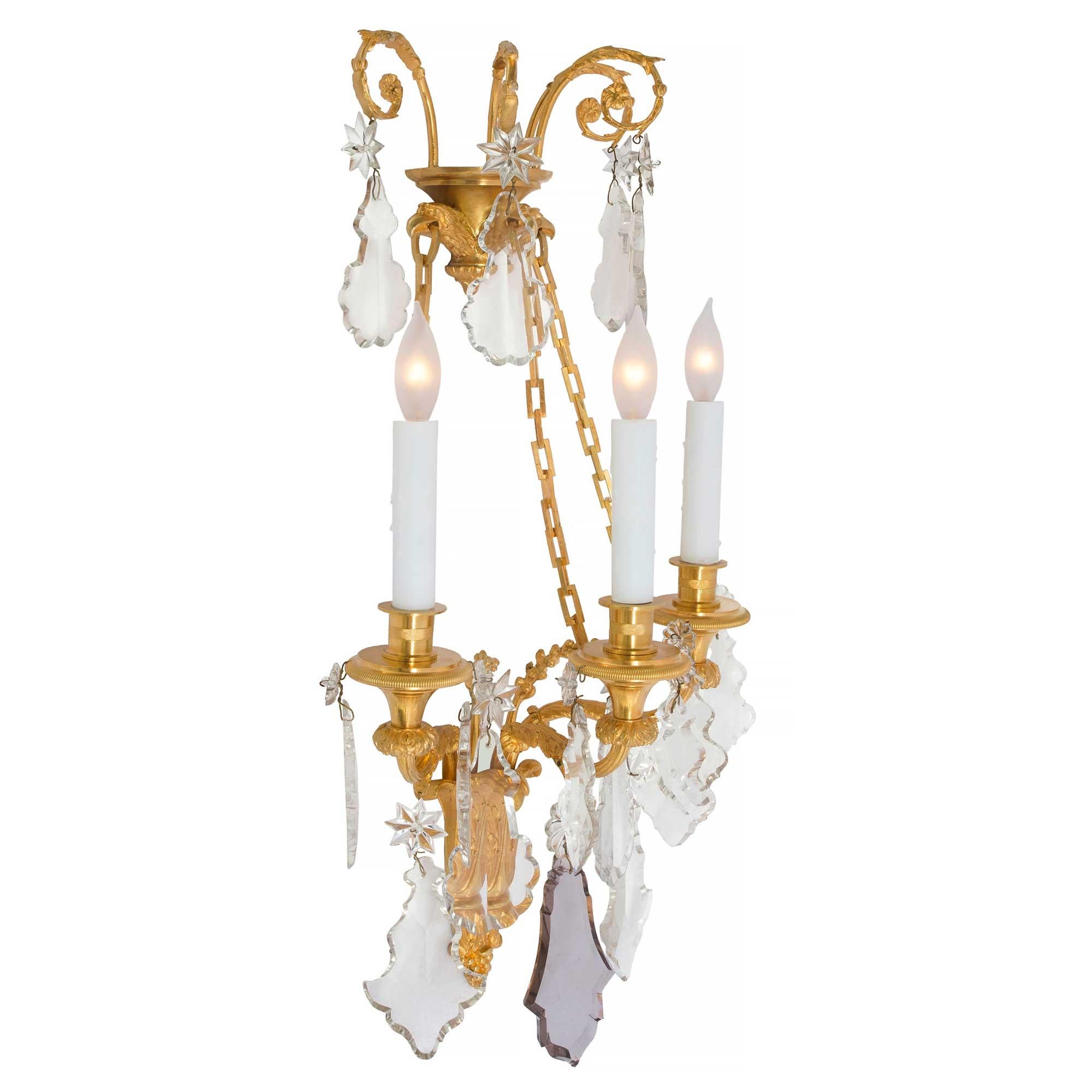 A pair of magnificent French 19th century Louis XVI style Baccarat crystal and ormolu three light sconces. Each sconce is centered by a striking acorn finial below richly chased acanthus leaves in a fine satin and burnished finish. Each of the
