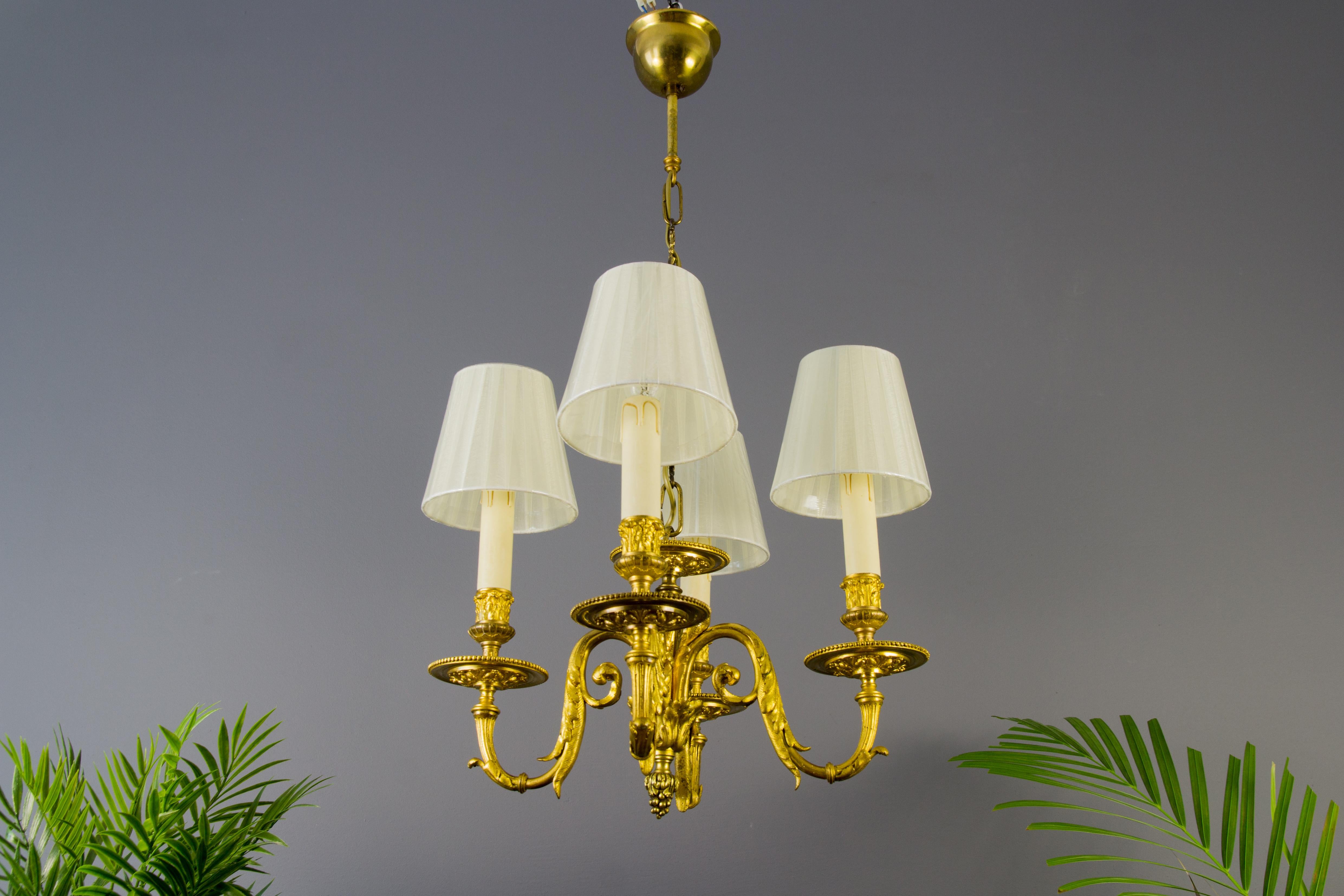 An exquisite French Louis XVI style four-light chandelier. Originally crafted for 4 candles, this antique chandelier has been electrified. Beautiful finely made bronze foliate motifs. Four bronze arms, each with a socket for the E 14 size light bulb