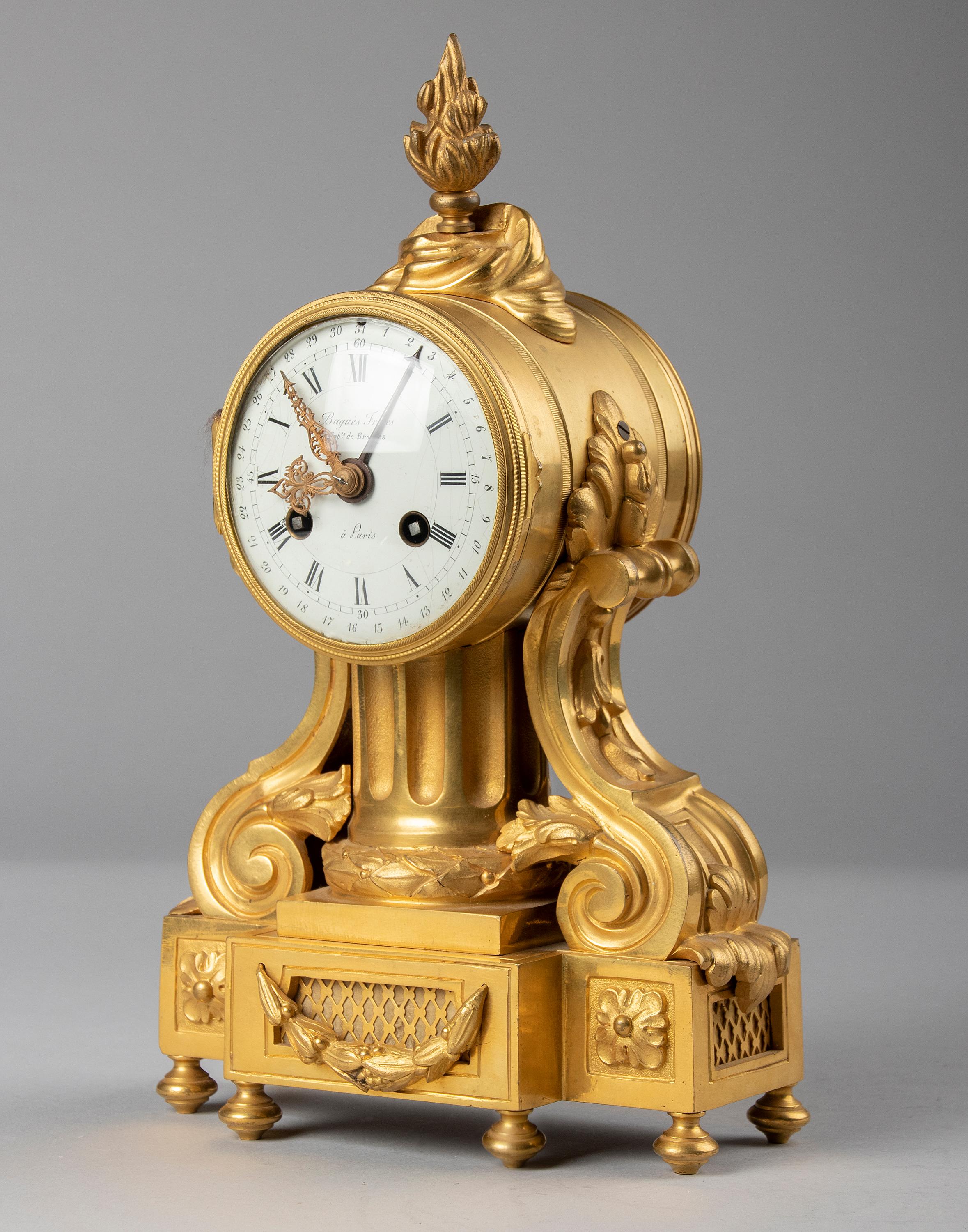 A fine quality Louis XVI style bronze ormolu mantel clock. The case is made of gilt brass and bronze ormolu casted ornaments, the dial is enameled iron. Ornated with neo-classical ornaments, laurel wreath, fluted column, torch and scrolled sides.