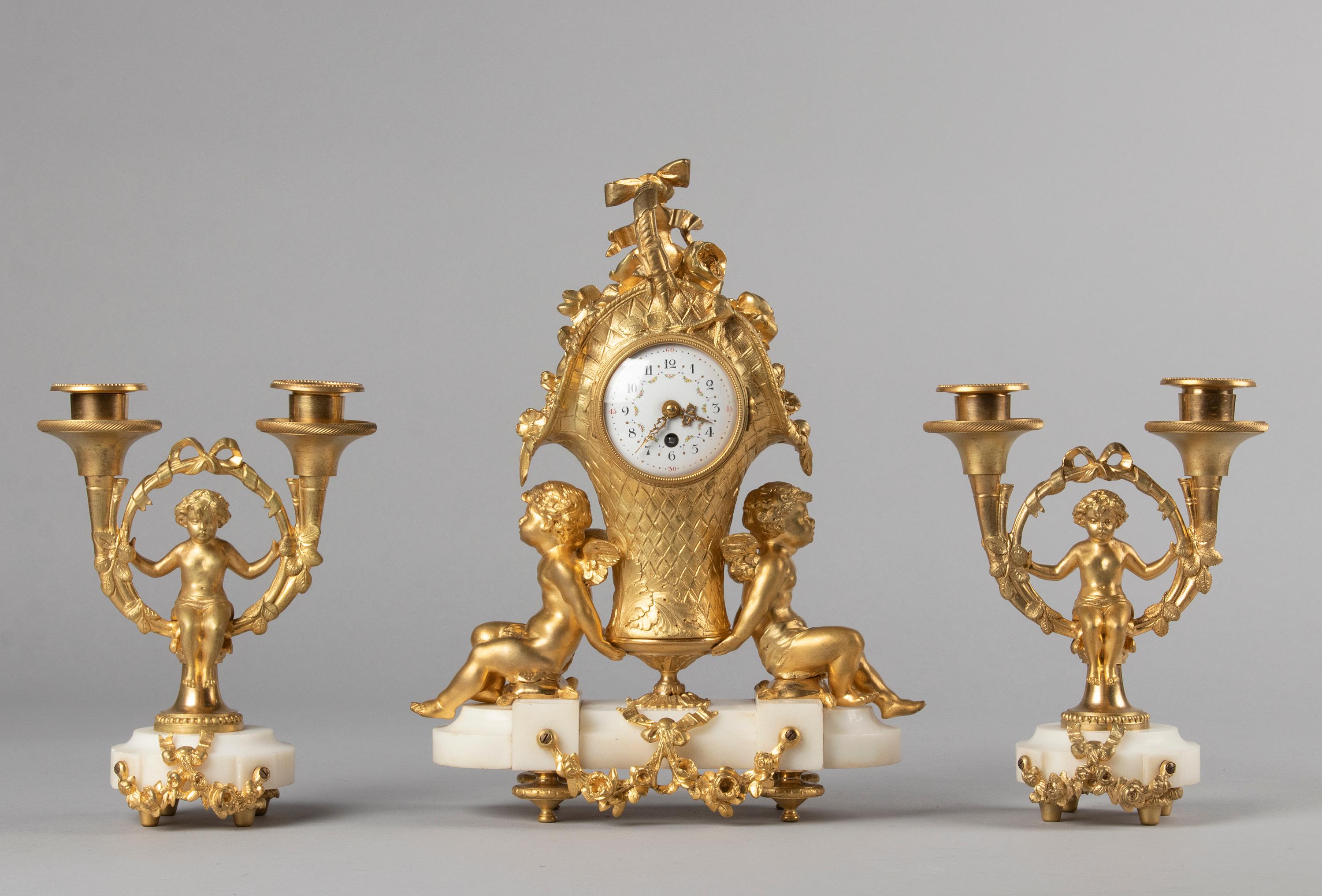 Eine sehr schöne figurale Kaminuhr im Louis XVI-Stil mit passendem flankierenden Kandelaber. Die Uhr ist aus Bronze gegossen und hat ein Ormolu-Finish, das Zifferblatt ist aus emailliertem Eisen. Auf einem Sockel aus weißem Marmor ruhend. Reichlich
