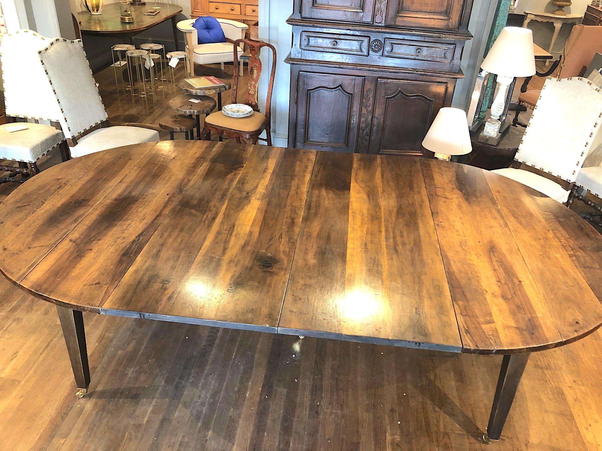 Fine quality 19th century Louis XVI style French Provincial extending dining table made of beautifully patinated and very highly figured Circassian walnut with five straight tapering legs and casters. A large oval table extending with two leaves