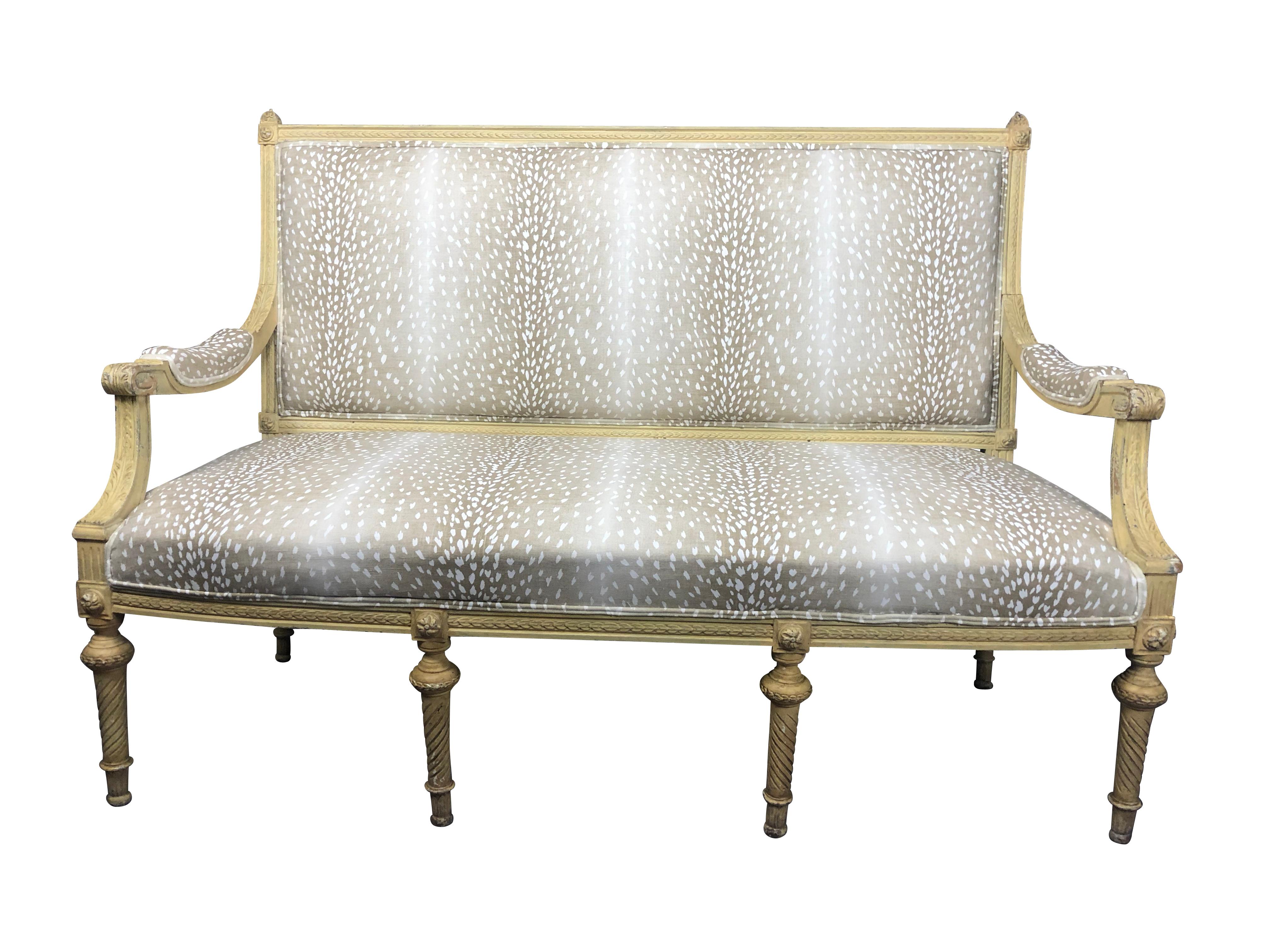 19th century Louis XVI French style settee in antelope fabric, original cream painted French settee with carved foliate, and rosette design. Newly reupholstered in light taupe antelope print fabric. Turned legs, with a pleasing amount of paint loss