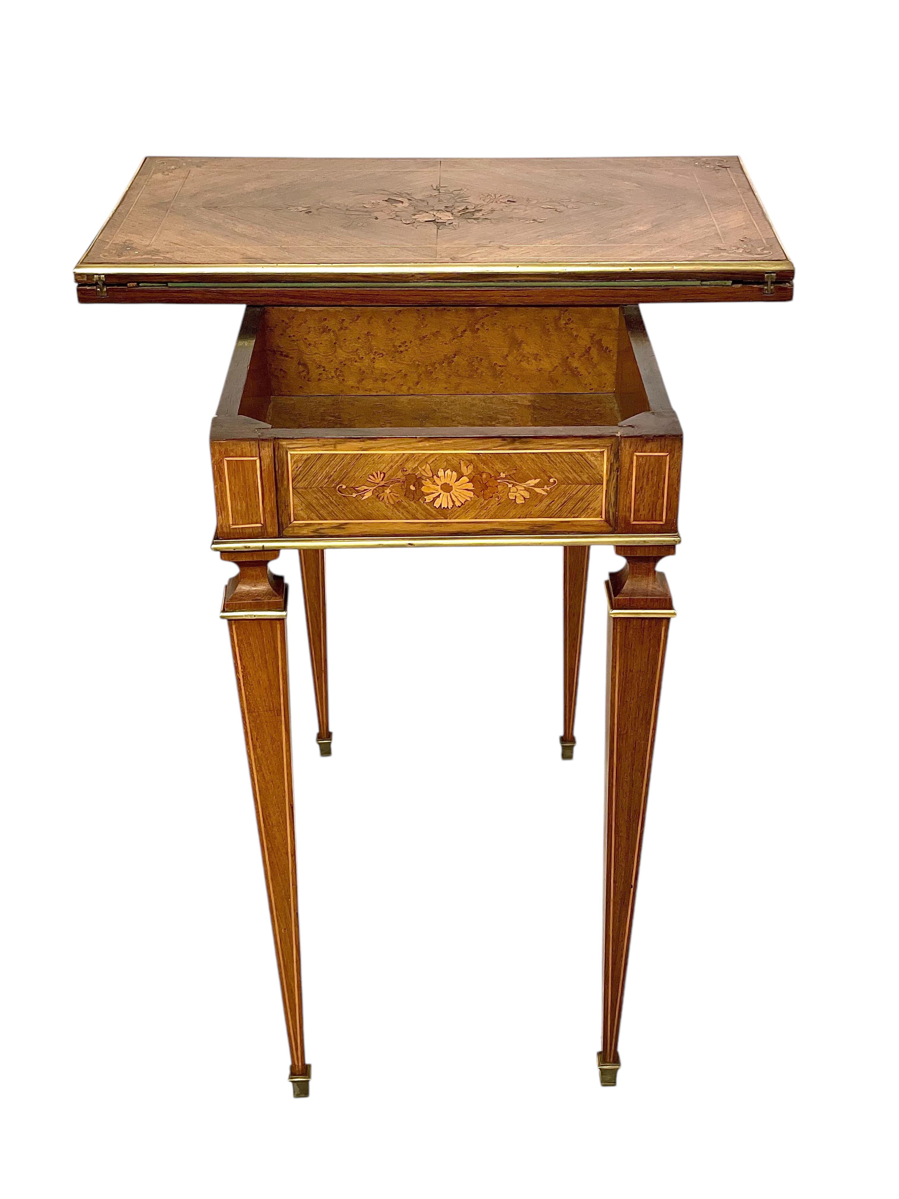 Esta exquisita mesa de juego del siglo XIX combina la elegancia del estilo Luis XVI con una notable artesanía y funcionalidad. Su estructura rectangular de madera está adornada con intrincadas incrustaciones de marquetería floral en el delantal y el