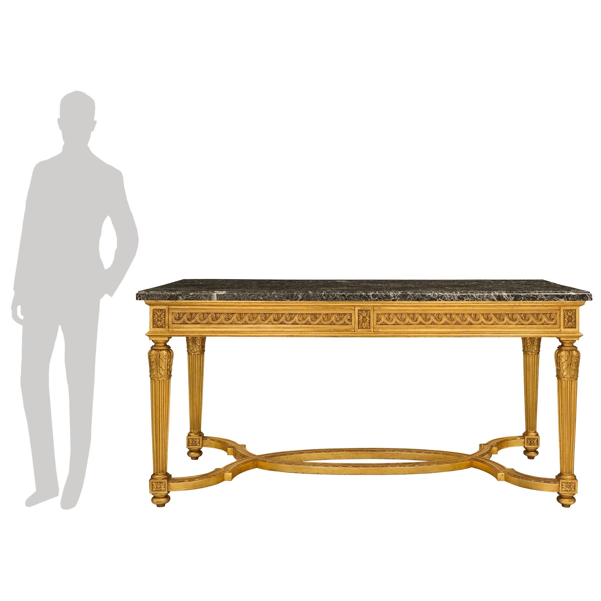 A stunning and extremely high-quality French 19th century Louis XVI style giltwood and Vert Antique marble center table. The large-scaled rectangular two-drawer center table is raised by elegant mottled bun feet below square block rosettes and