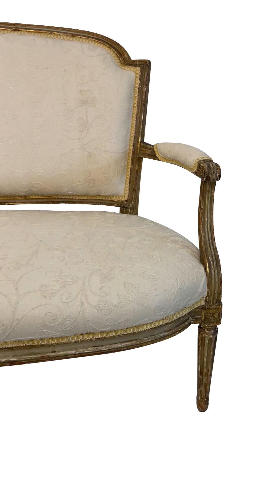 A classic 19th-century Louis XVI giltwood canape or settee upholstered in a cream-on-cream embroidered fabric. Original horsehair upholstery stuffing has been retained under the new fabric. 36 H X 54.5 W X 20 D 