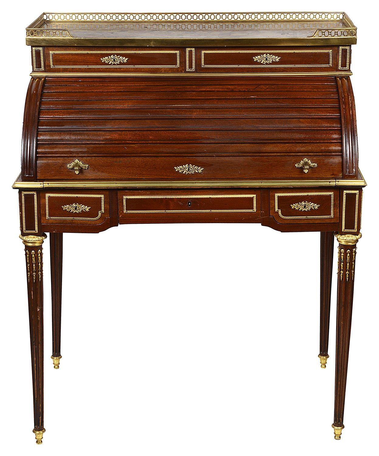 A very good quality late 19th Century French Louis XVI style Mahogany tambour bureau, having a marble top with a brass gallery. Pigeon hole compartments and drawers within, gilded omolu moldings, two frieze drawers and raised on turned tapering
