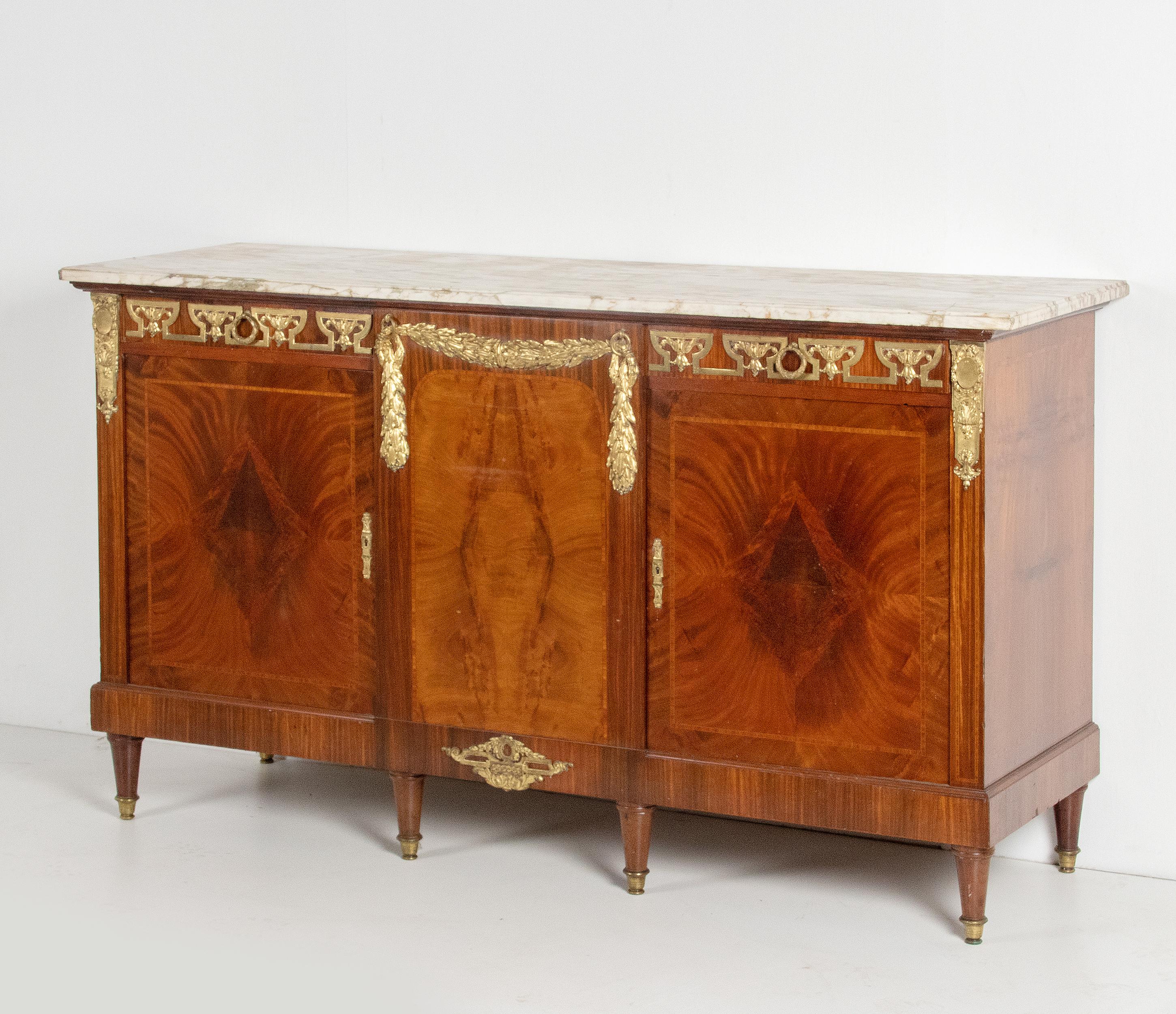 An antique French veneered Louis XVI style 2-door sideboard. The furniture was made in the late 19th century, about 1880-1890. This dresser is decorated with gilded bronze fittings, in the centre a ormolu bronze garland in the middle. The cabinet