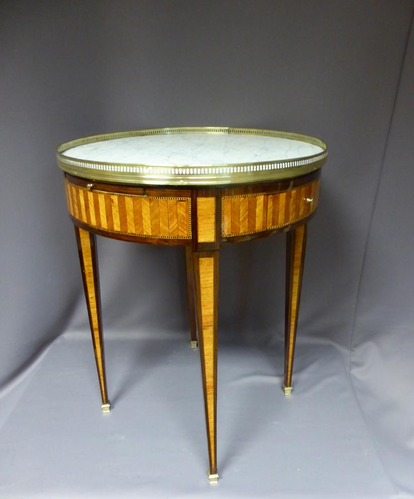 19th century Louis XVI style marquetry Bouillotte table. The marble top is surrounded by a brass gallery. This table has two drawers and two zippers covered with green leather.
The ends of the feet are finished with bronze hooves.