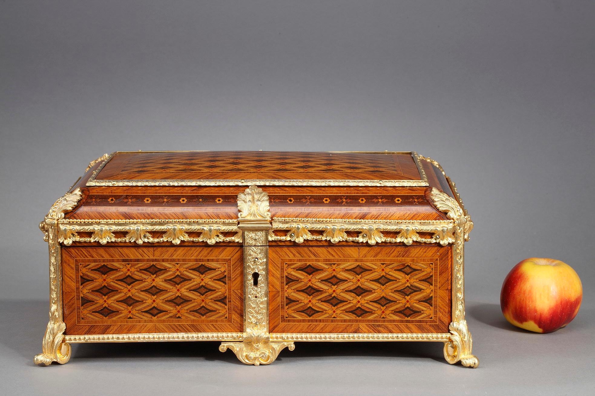 Geometric marquetry pattern and faithful interpretation of the Louis XVI style characterize this 19th-century French jewelry box. Enfolded in intricate marquetry featuring diamond pattern, the casket is mounted in gilt bronze, chiseled with delicate