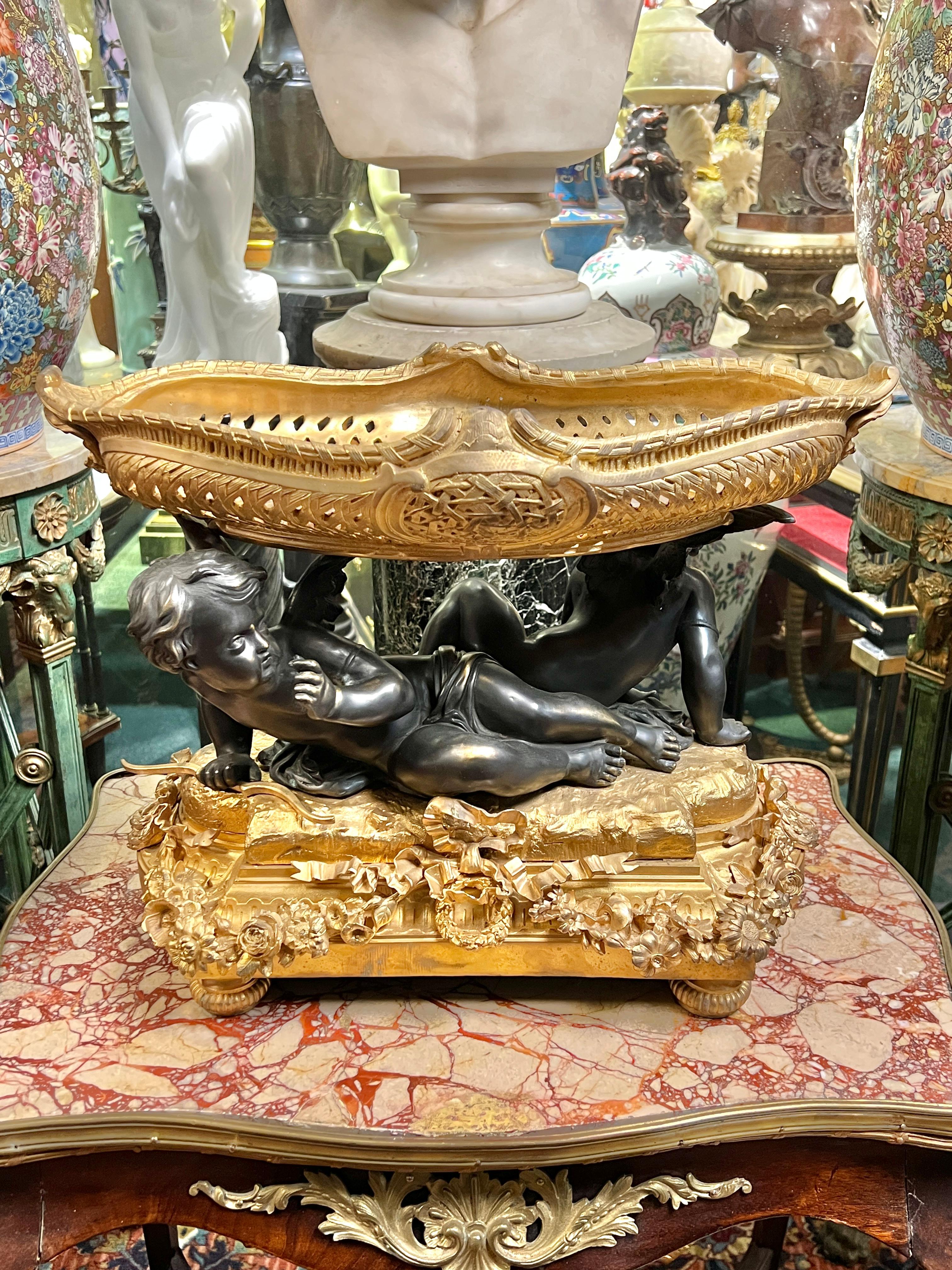 Jardinera o cuenco de centro de mesa francés finamente fundido, patinado y dorado, de estilo Luis XVI, según el modelo original de Mathurin Moreau (1822-1912), que representa a Cupido con su arco y un querubín de compañía.  20 pulgadas de ancho, 14