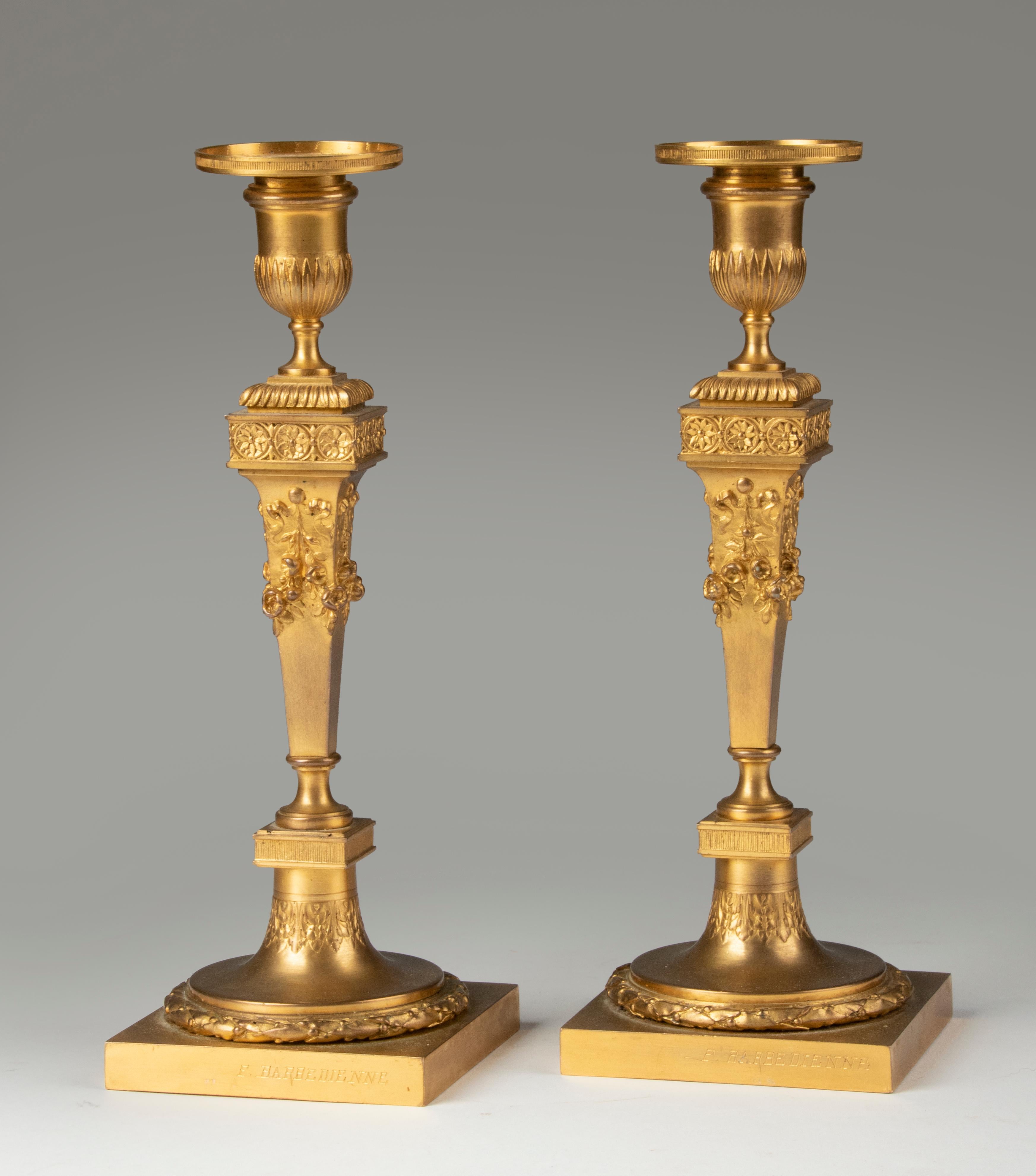 A pair of refined bronze fire-gilt candlesticks in Louis XVI style. Signed Ferdinand Barbedienne Foundry. The candlesticks are made of casted bronze with an ormolu fire-gilt finish. Typical Louis XVI style elements, such as laurel wreath around the