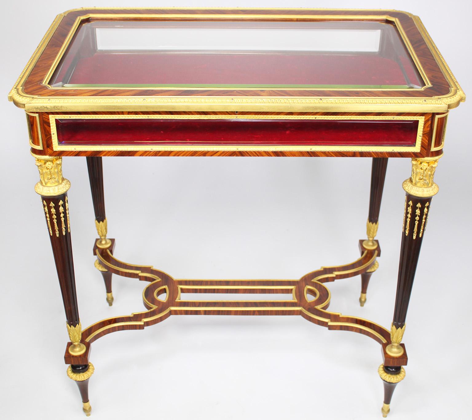 A Superb Quality French 19th Century Louis XVI Style Ormolu Mounted Mahogany and Kingwood Vitrine Table, Attributed to Henry Dasson (French, 1825-1896), with a beveled glass lift top and lined interior, fluted tapered legs and a shaped stretcher