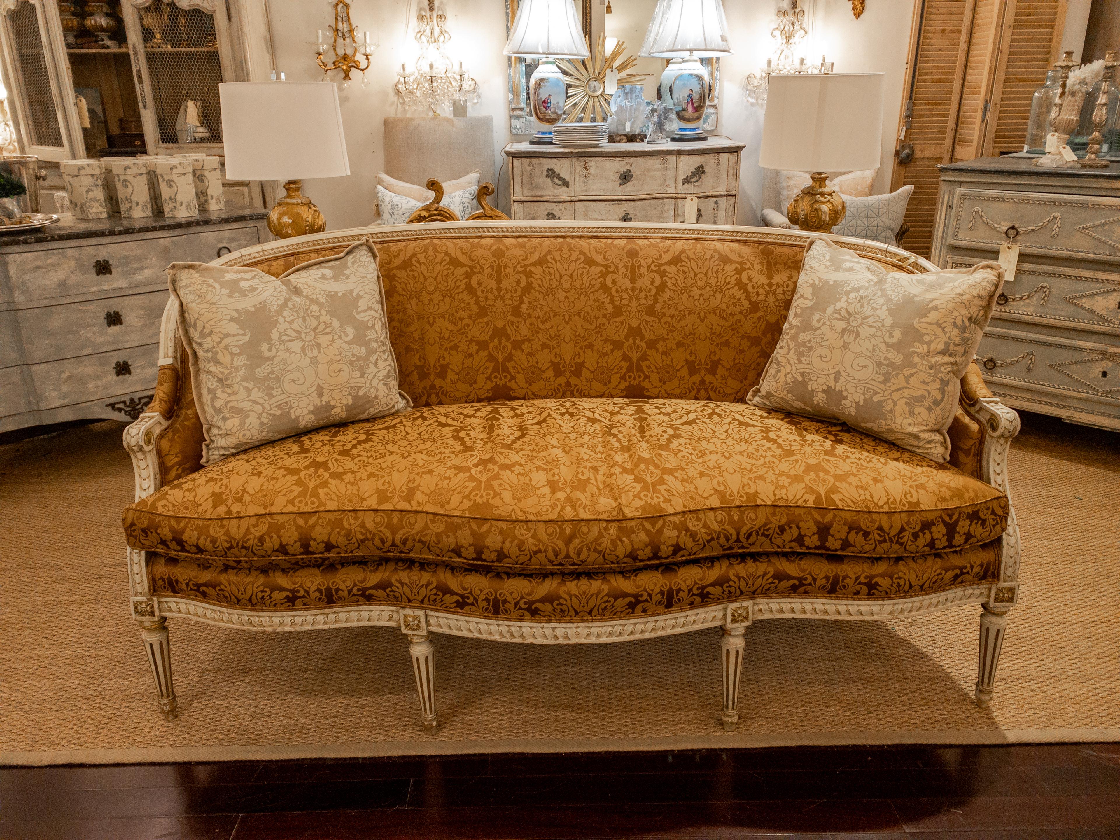 The 19th Century Louis XVI Style Painted Settee is a striking piece of furniture that exudes elegance and charm. Its serpentine front shape and rounded backrest are distinctive features that capture the essence of the Louis XVI design aesthetic.