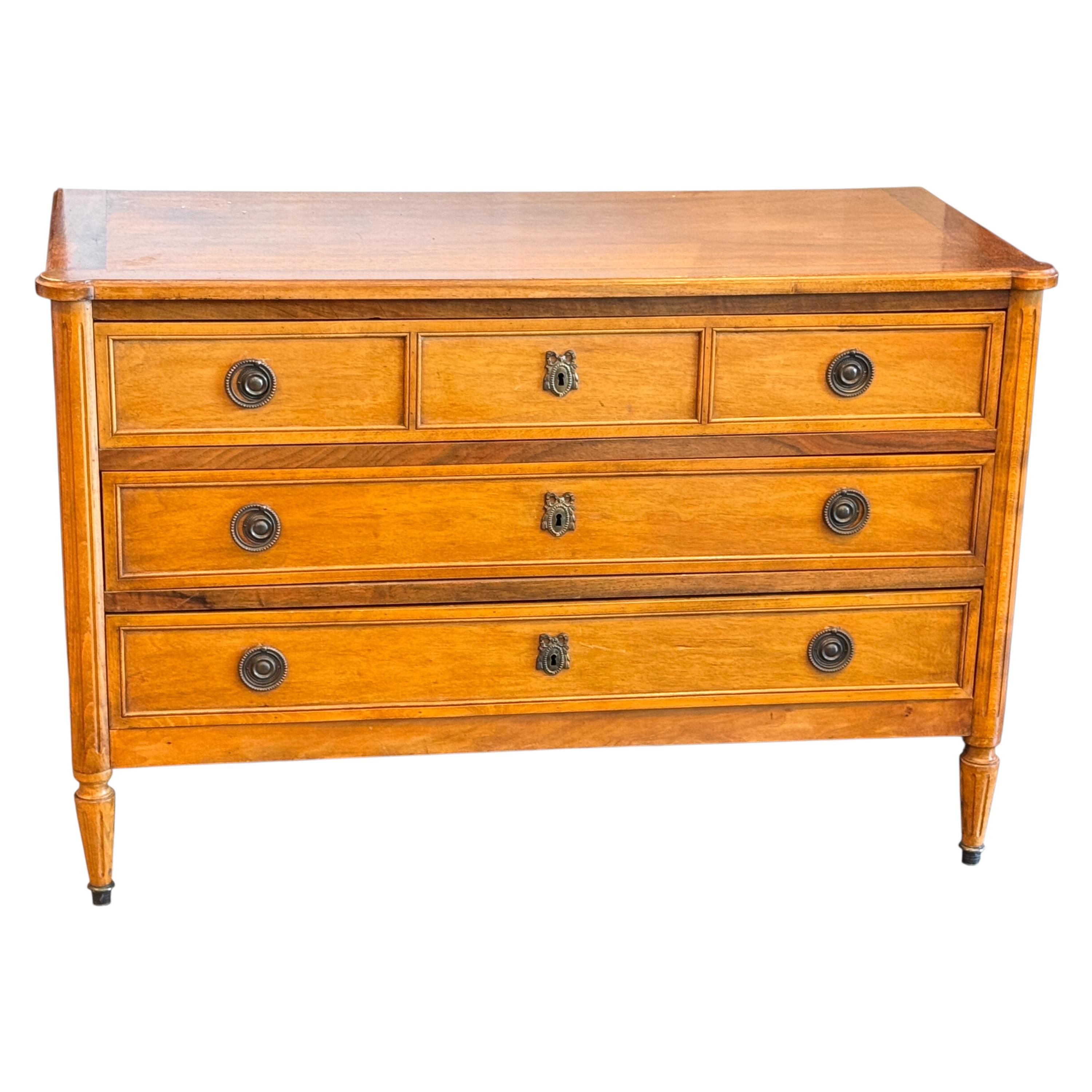 Una commode in noce del XIX secolo in stile Luigi XVI, caratterizzata da linee pulite, gambe scanalate e tiranti originali in ottone. La cassa presenta due cassetti stretti sopra due cassetti a tutta larghezza, ognuno dei quali è delineato da una