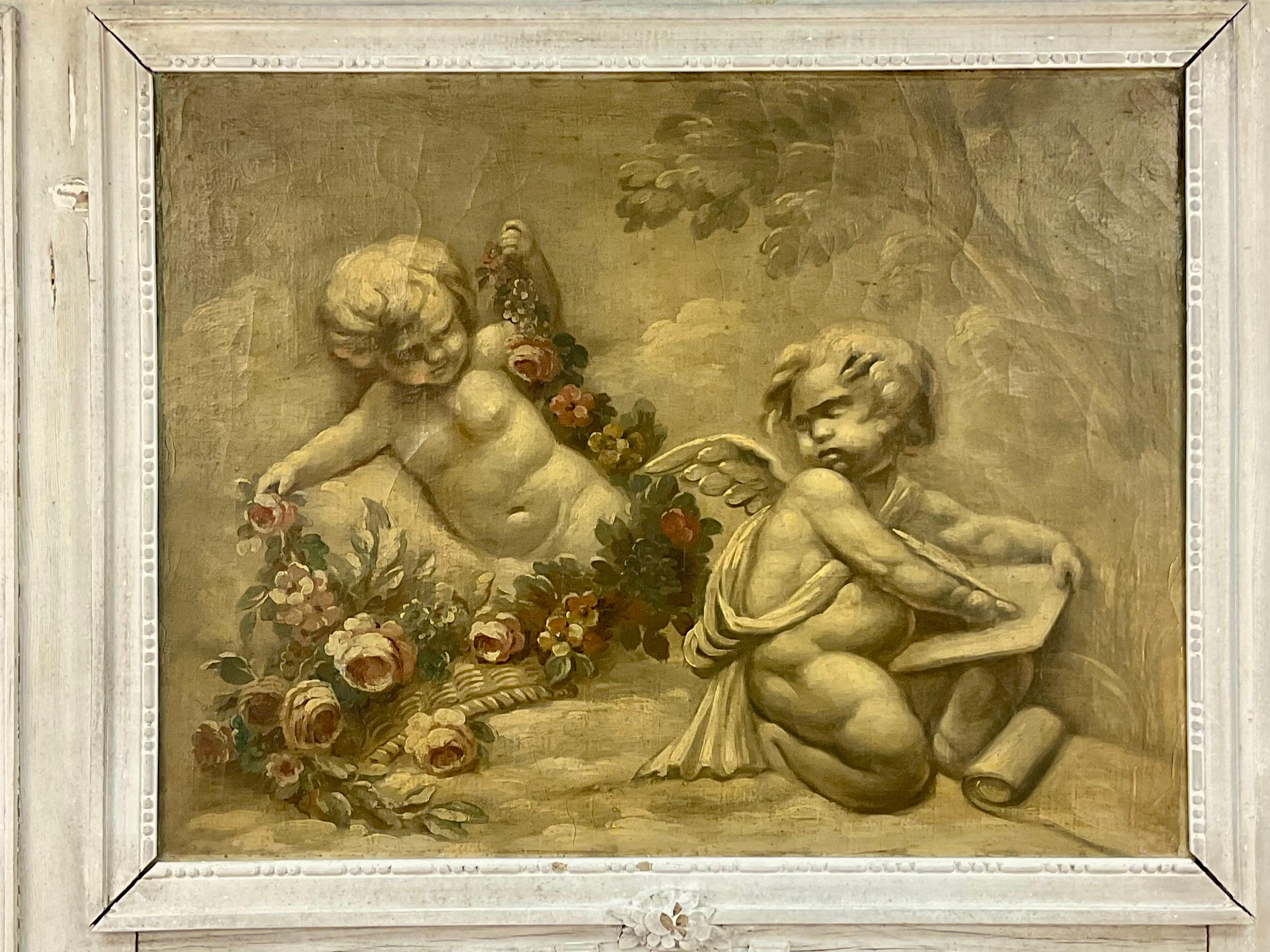 Charming Trumeau mirror with a painting of two cherubs sitting among pink flowers with green leaves. Mirror below is set into a tall wooden frame with carved sculptural decorations and painted in white. 