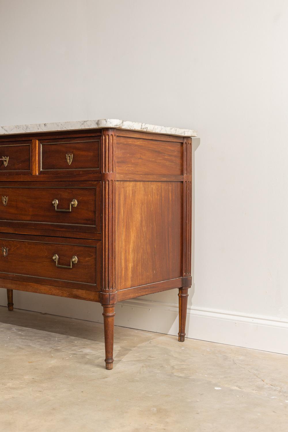 This Louis XVI Walnut commode is a truly stunning stained piece with original bronze hardware and working lock and key. The dark stain contrasting with the cream colored marble top gives this piece a beautiful moody feel. It was manufactured in 1850