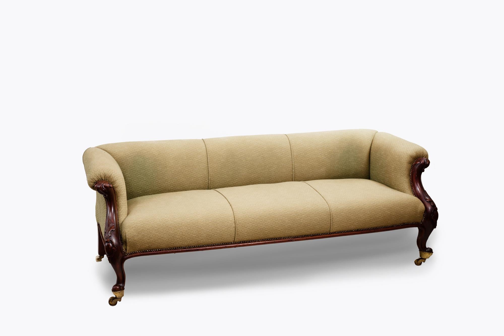 19th Century low back sofa with carved arms, over long seat raised on cabriole legs with acanthus leaf detailing terminating on original brass castors.