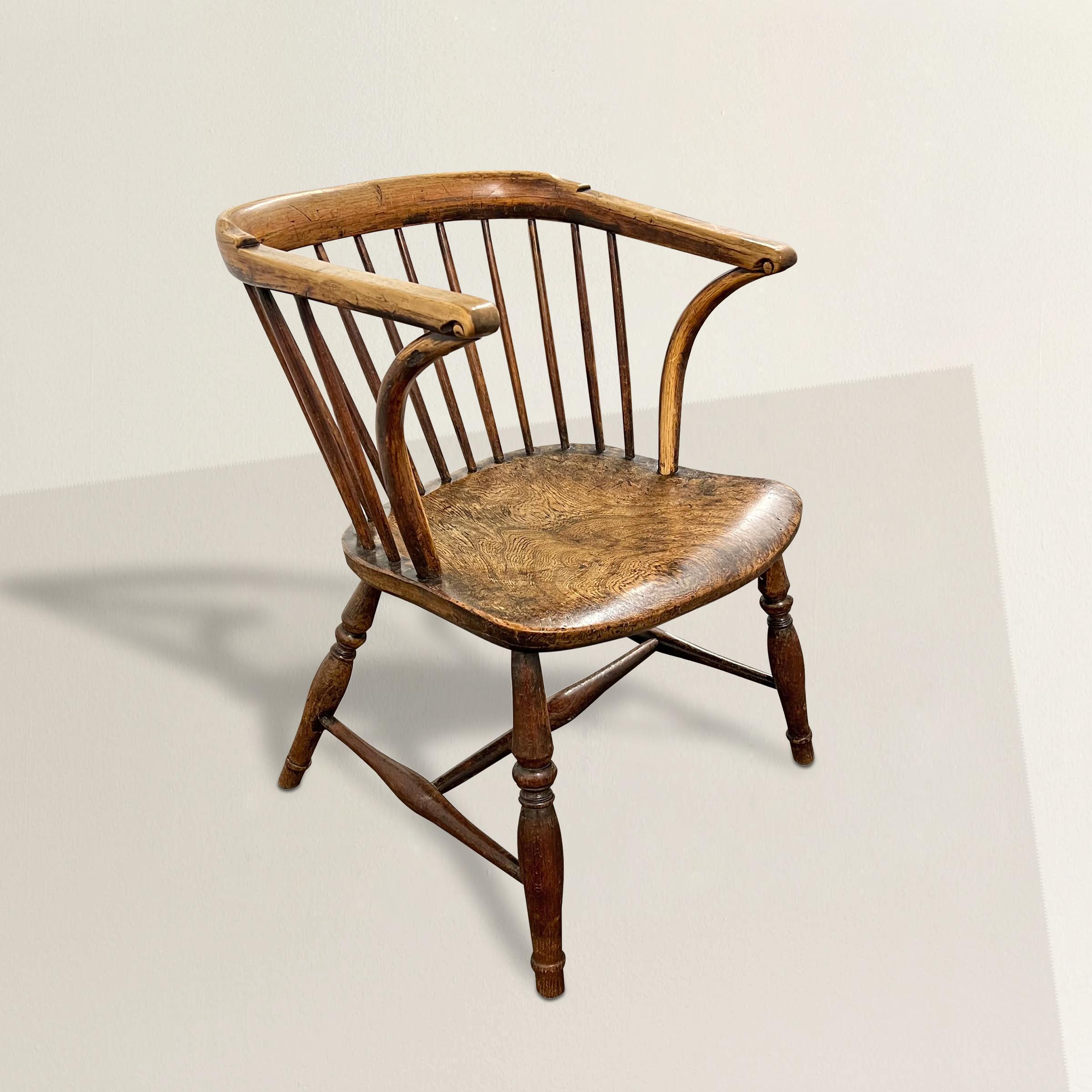 This charming mid-19th century English low back Windsor chair is a testament to the craftsmanship and enduring style of the era. The chair features a distinctive bent yew wood crest rail, its graceful curve supported by a rhythmic arrangement of