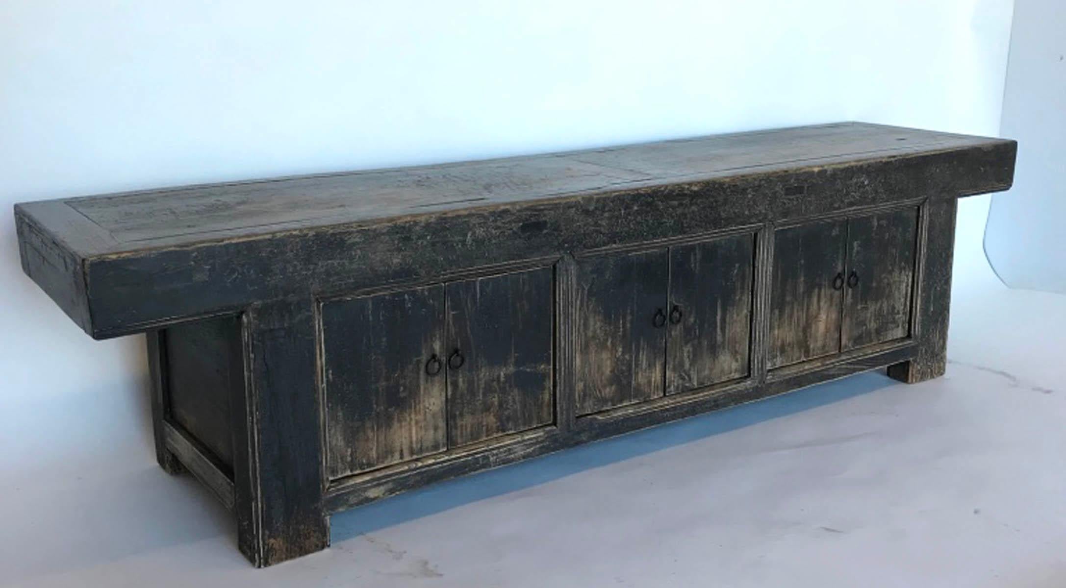 This old piece with a worn black finish showing underlying wood has a beautiful antique patina. It has mortise and tenon construction throughout. Three equally spaces storage spaces behind three equally spaces pairs of doors. Would work beautifully