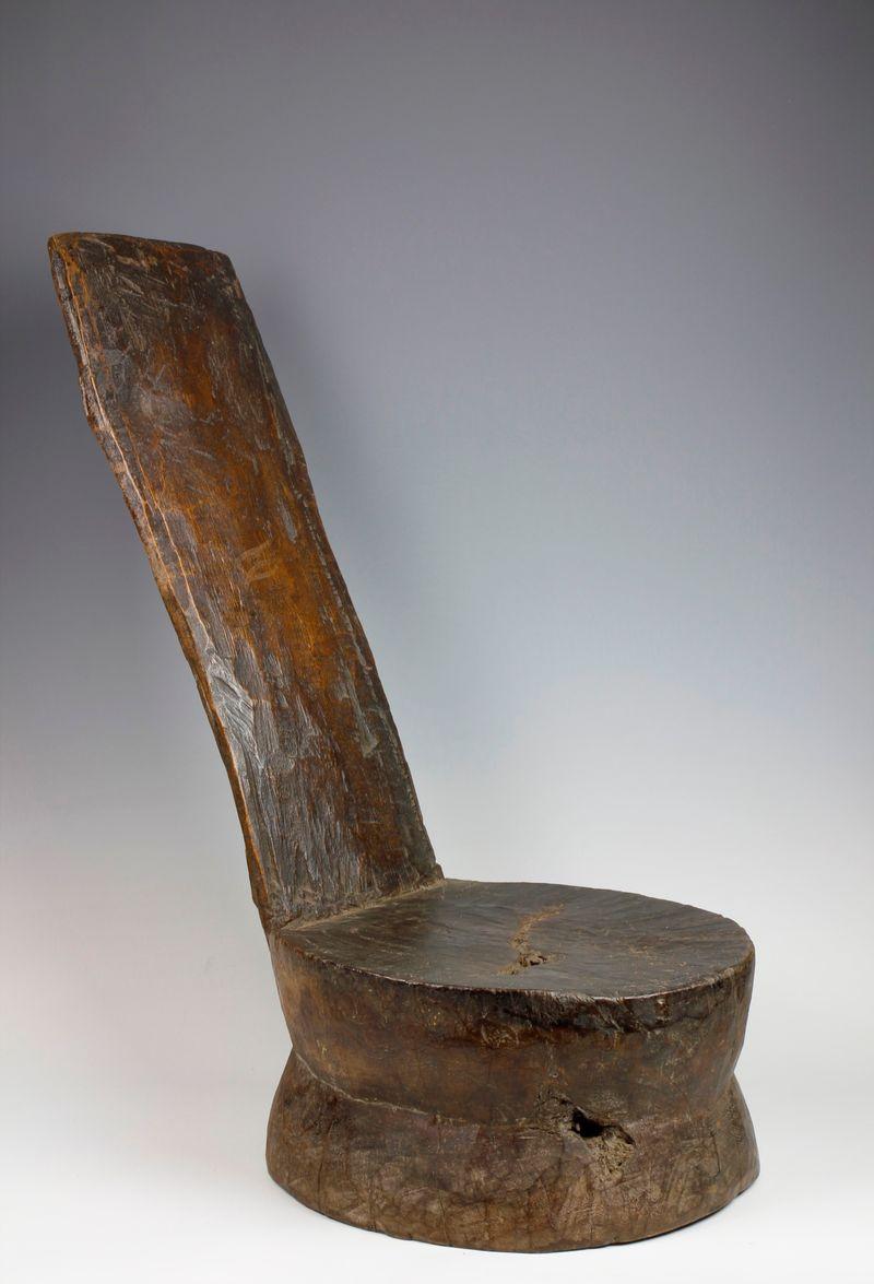 Carved from a single piece of dense, heavy wood, this nineteenth-century Gurage low-set chair from Ethiopia exhibits an unusual, rare form. Consisting of a circular double-tiered seat with an angled, reclining back-support, the chair exhibits a deep