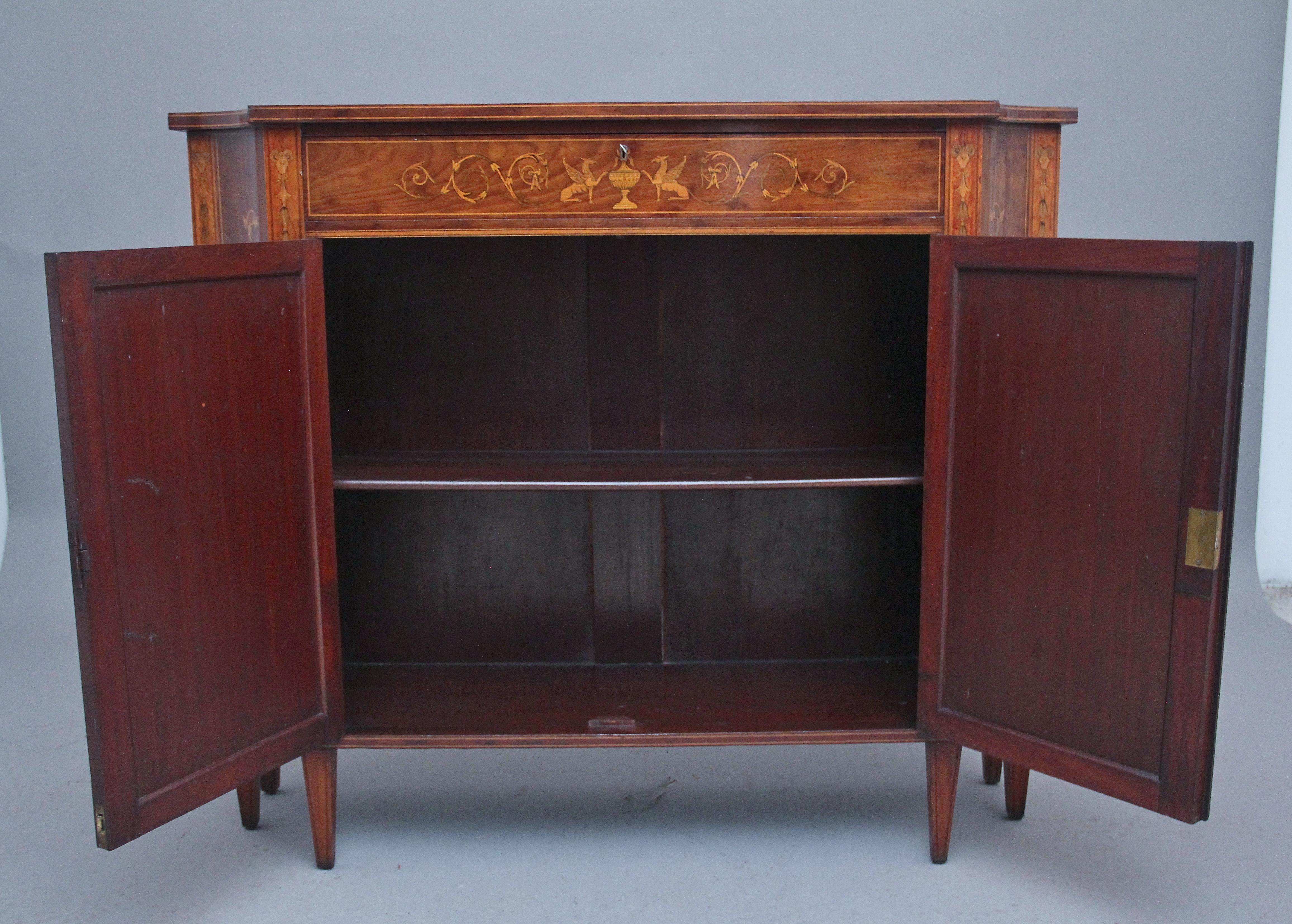 A highly decorative 19th Century mahogany and inlaid side cabinet in the Sheraton style, having a nice figured shaped top with decorative inlay incorporating various masks, musical instruments and foliage, single mahogany lined frieze drawer below