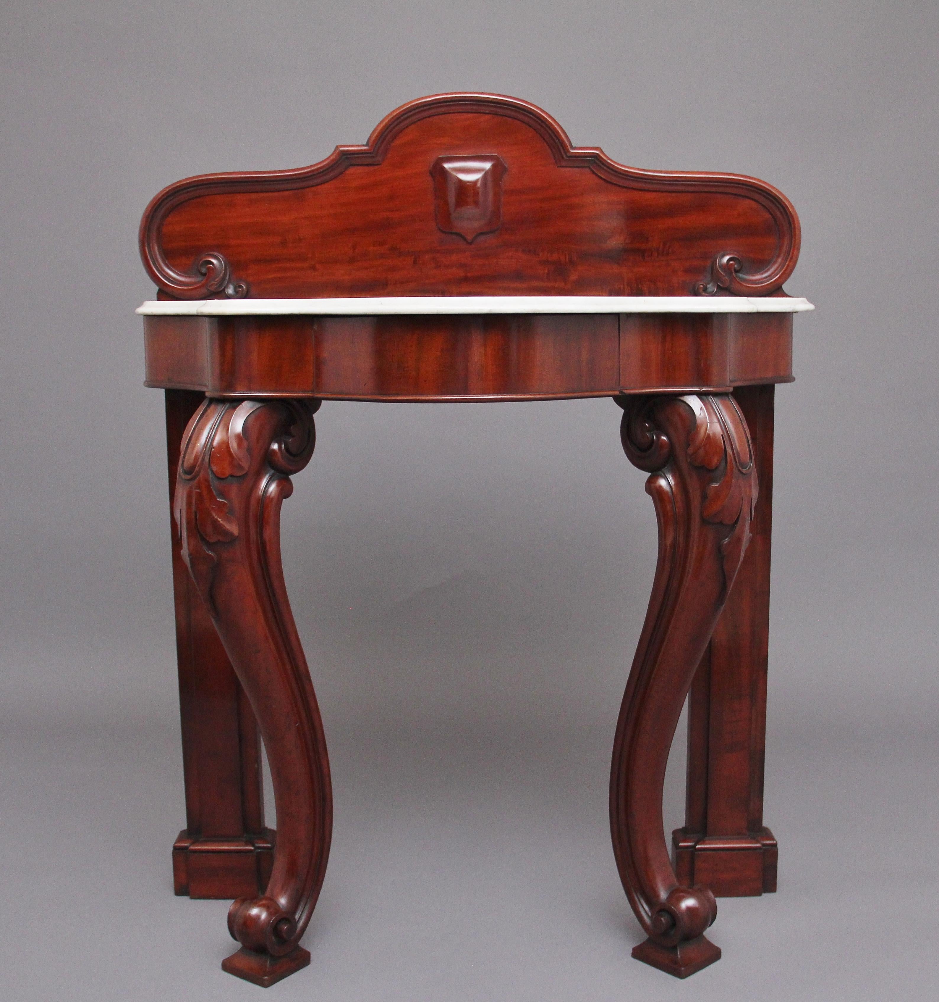 19th century mahogany and marble top consul table, having a shaped and carved back with a decorative moulded edge, the table having the original shaped white marble top with a moulded edge, a central frieze drawer below, supported on rear square